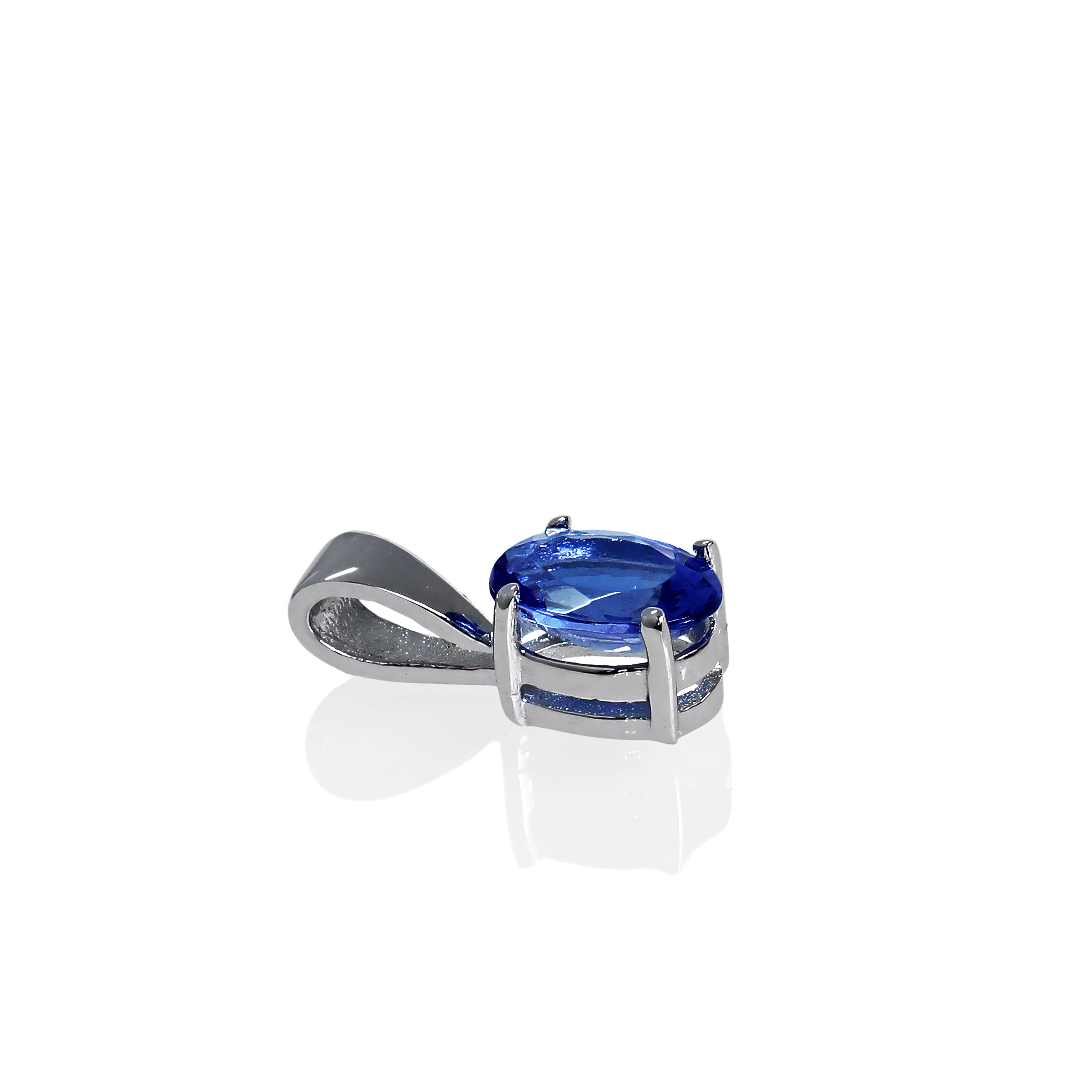 A product photo of a white gold tanzanite pendant suspended by a chain against a white background. The oval stone is held in place by 4 small claws, and reflects violet blue and indigo colours from its many edges.