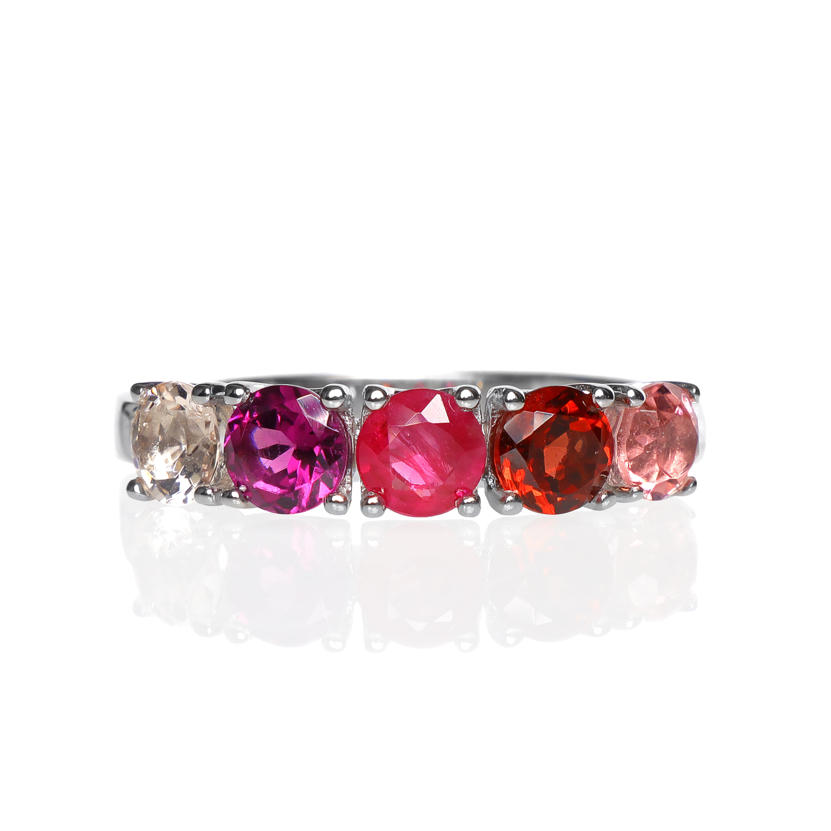 A product photo of a bold, multi-gemstone ring in 9k white gold – made up of 5 pink & red coloured jewels – sitting on a white background. From left to right, 4.5mm round-cut pink tourmaline, garnet, ruby with stunning streaked inclusions, grape garnet and morganite stones make up a boldly feminine statement piece.