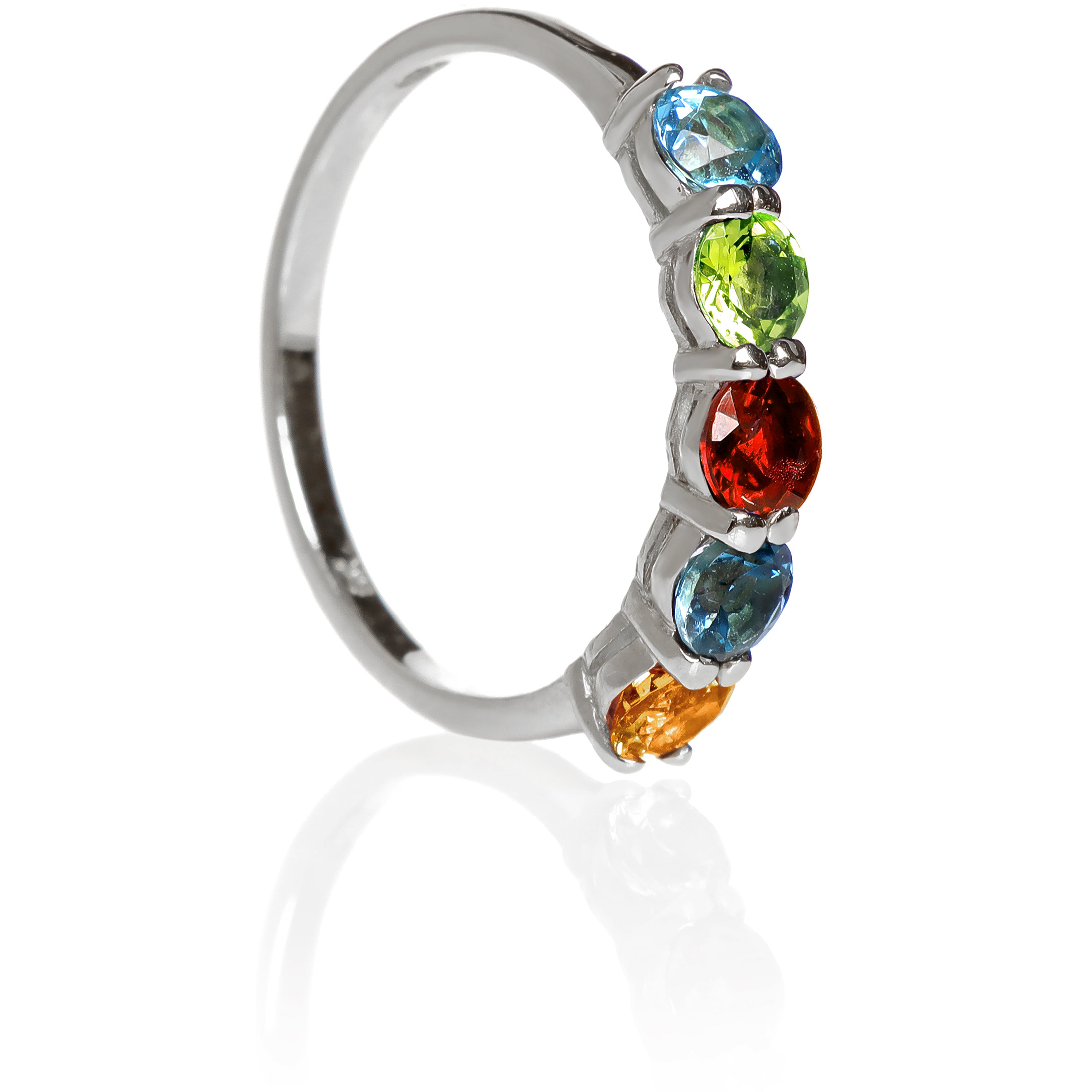 A product photo of a bold, multi-gemstone ring in 9k yellow gold – made up of rainbow-coloured jewels – sitting on a white background. From left to right, 4.5mm round-cut citrine, london blue topaz, red garnet, peridot and blue topaz.