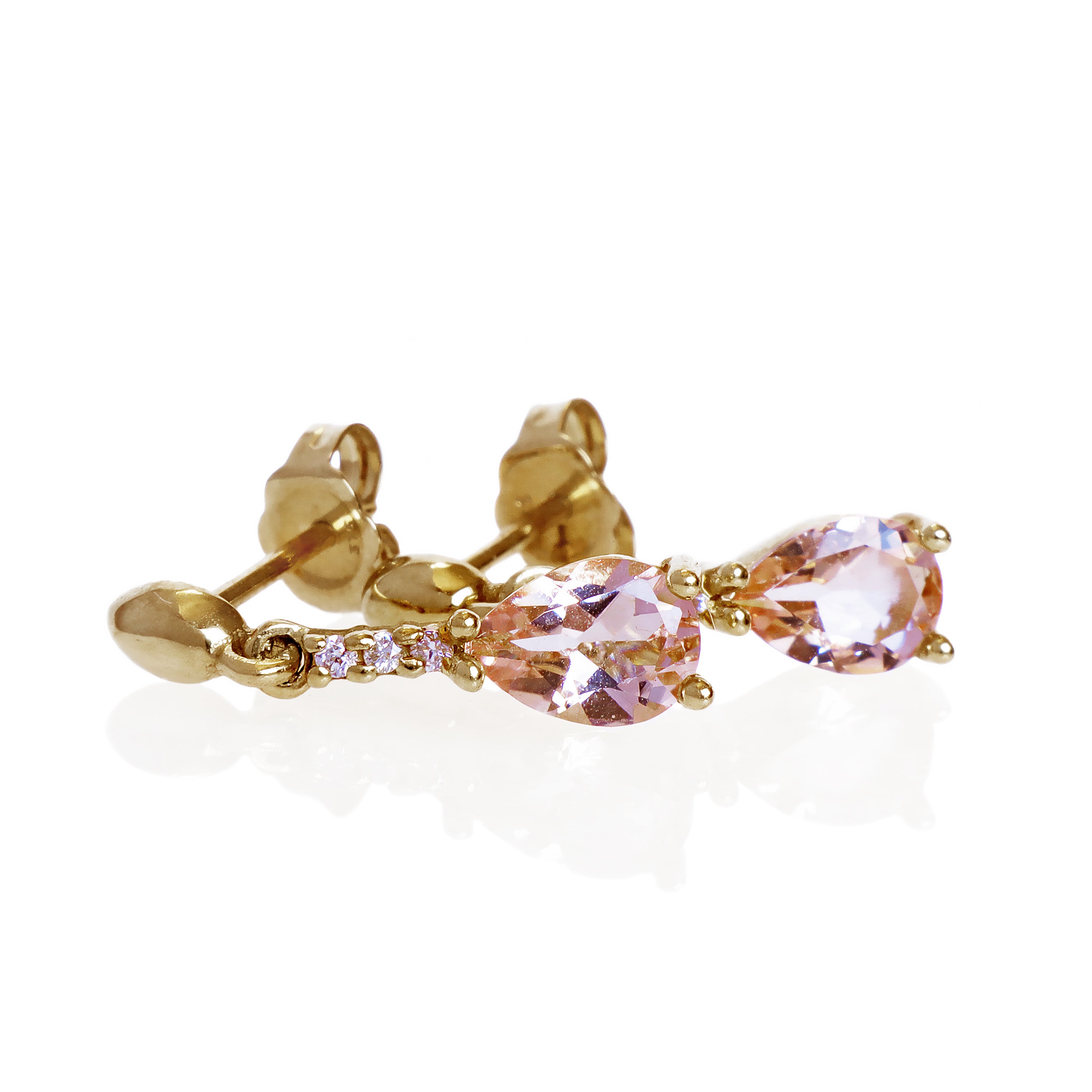 A product photo of 7x5mm Pear Morganite & Diamond Earrings in 9k Yellow Gold sitting on a plain white background. A golden strip connects the morganites to the studs, each strip adorned with 3 diamonds each. The morganites reflect light pinky hues across their multi-faceted edges.