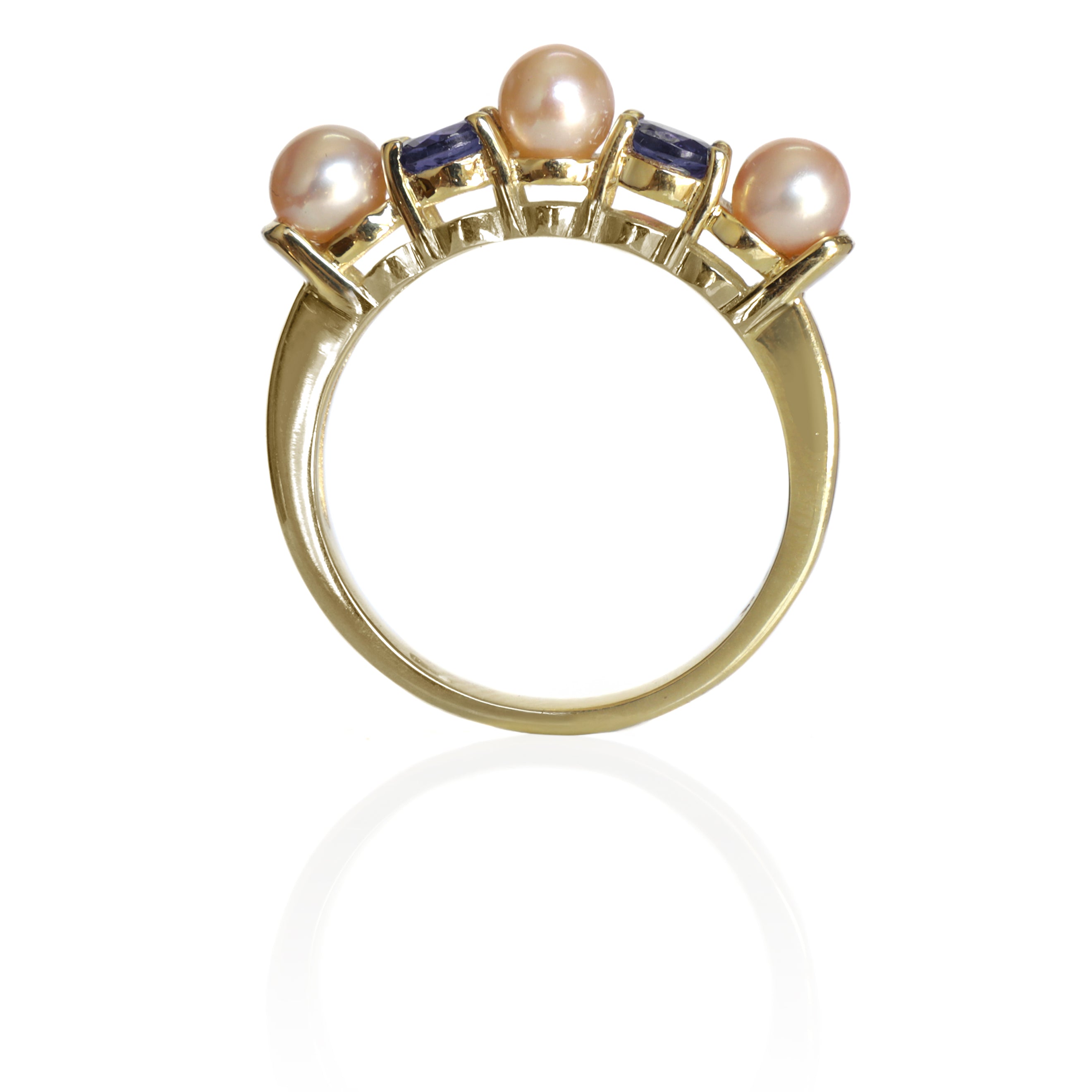 This product image shows a rosaline pearl and tanzanite eternity ring set in solid 9 karat yellow gold. The ring is made up of 3 round pale pink rosaline pearls of 4.5mm in diameter, two on the outer edges of the eternity design and one in the centre. Between each pearl sits an electric blue round-cut tsavorite jewel of similar sizing.