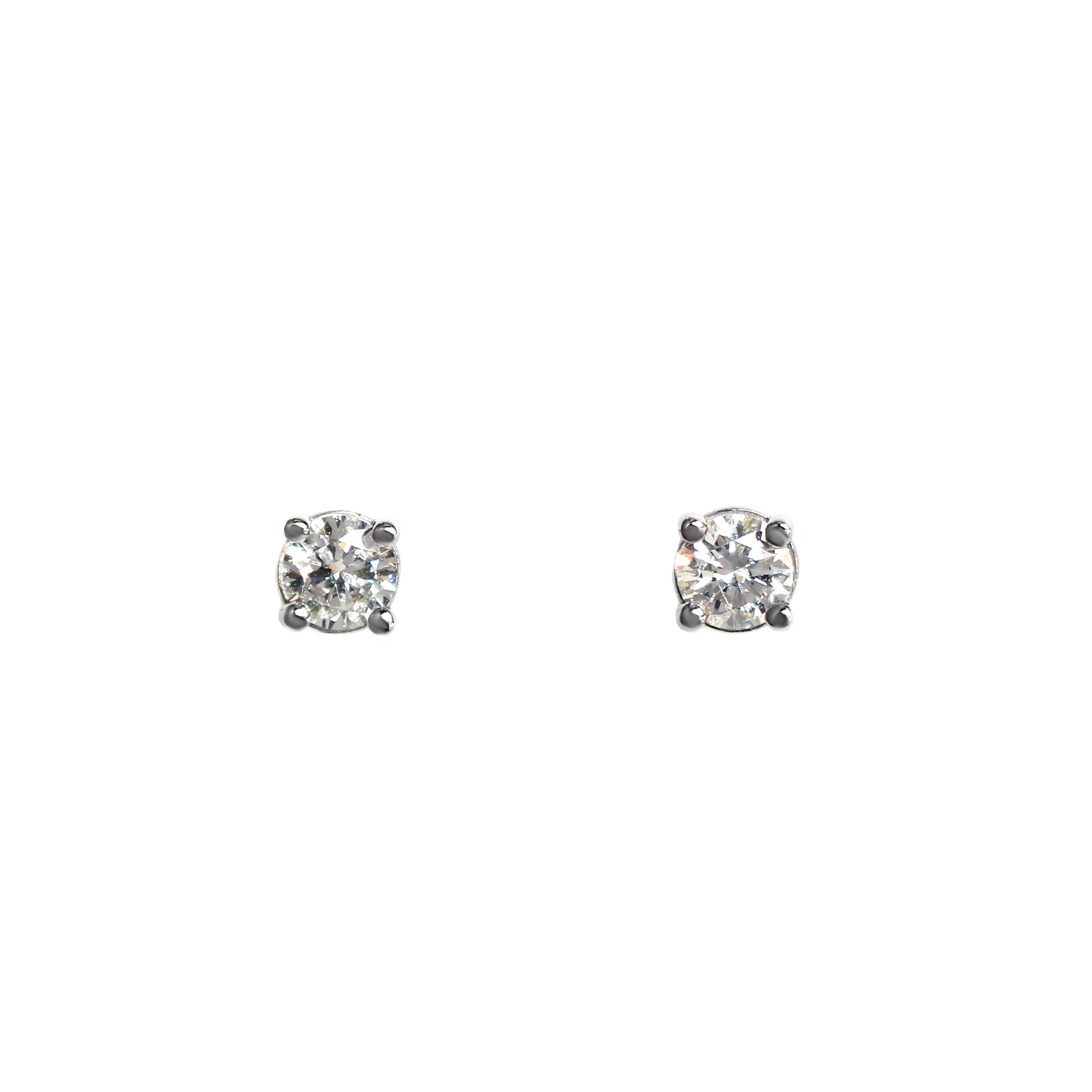 A product photo of a pair of 9 karat white gold lab diamond stud earrings sitting in the sun on a white textured background. The brilliant, colourless half pointer round diamonds measure approximately 3mm across, and are held in place by a simple 4-claw setting.