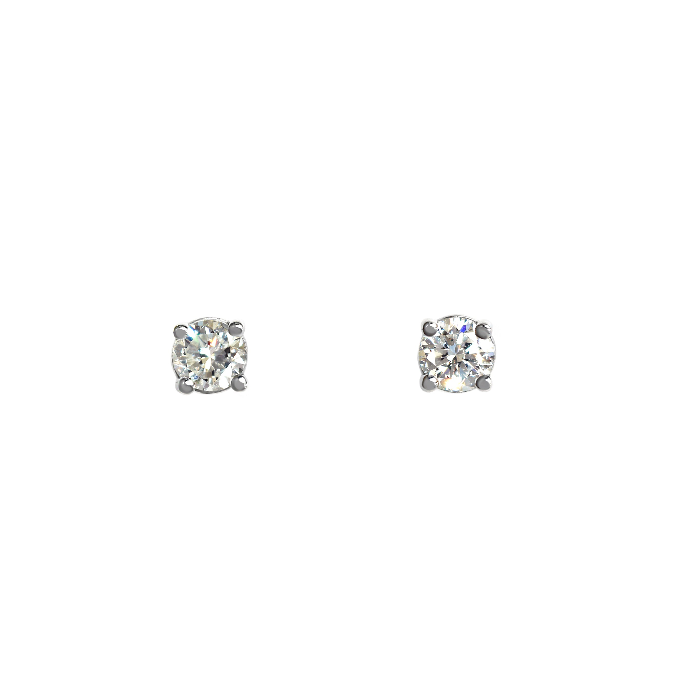 A product photo of a pair of 9 karat white gold lab diamond stud earrings sitting in the sun on a white textured background. The brilliant, colourless half pointer round diamonds measure approximately 3.5mm across, and are held in place by a simple 4-claw setting.