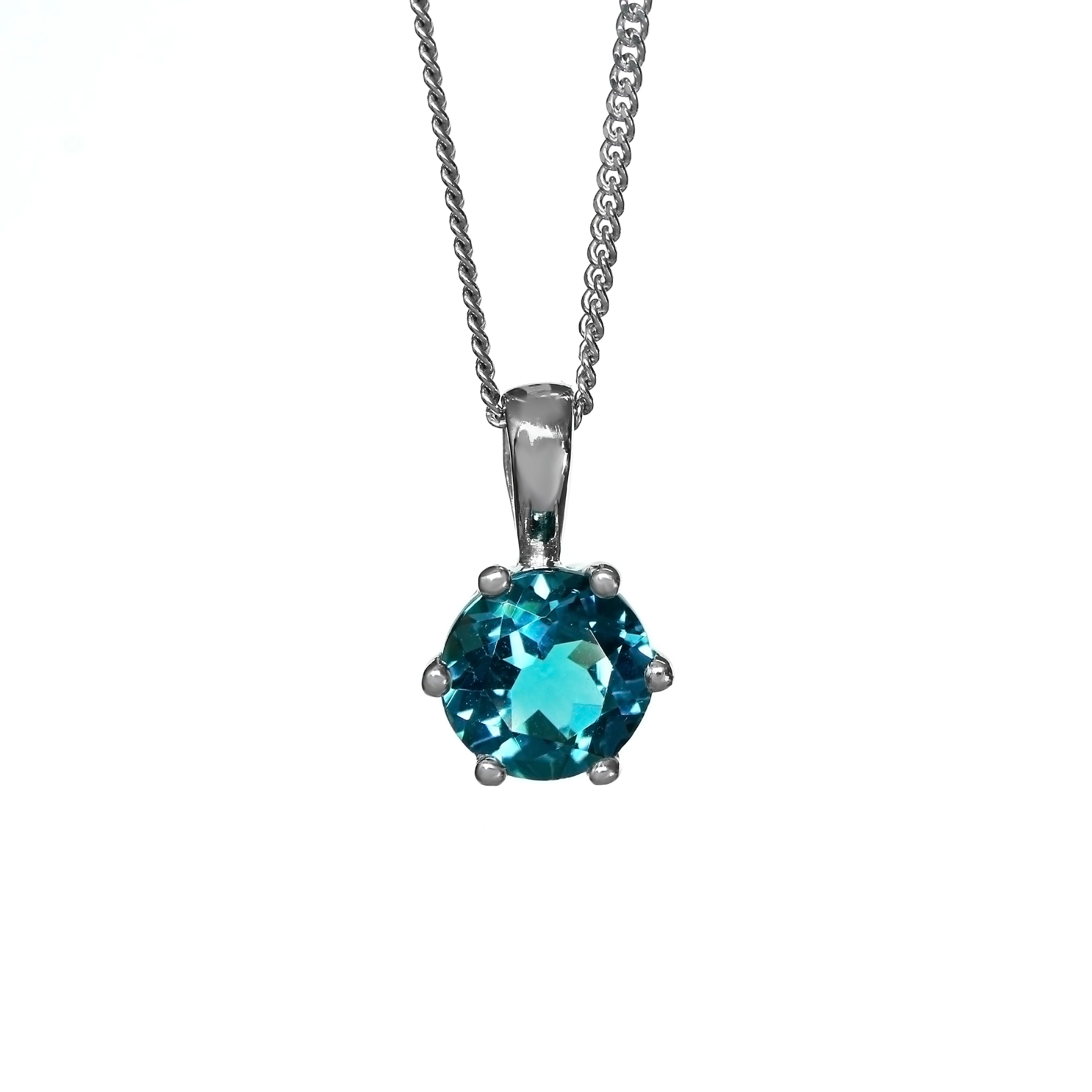 A product photo of a silver London Blue Topaz pendant against a white background. The highly-reflective round cut London Blue Topaz stone is held in place by 6 dainty silver claws. It is suspended by a simple silver chain.