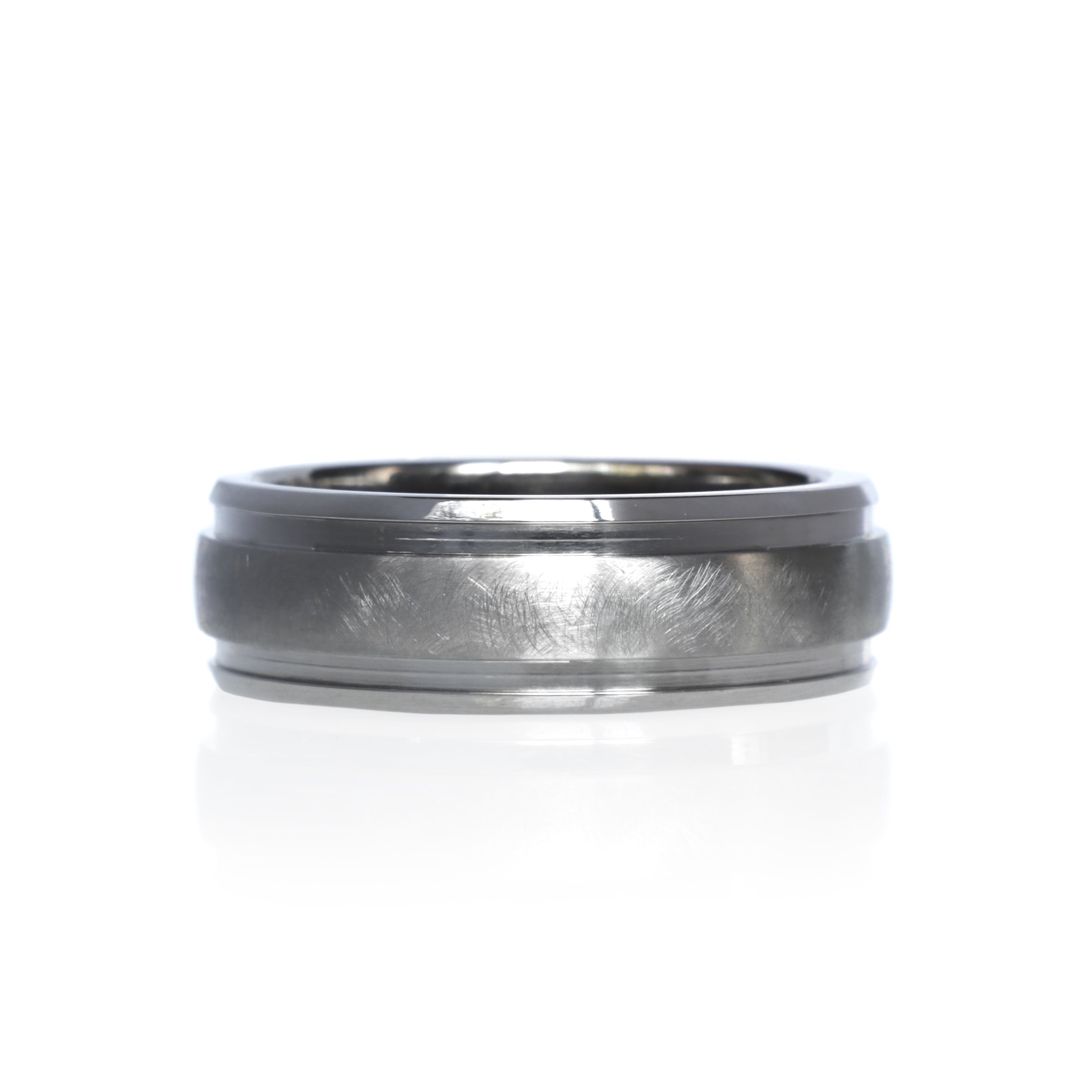 A product image of a 7mm wide ring against a plain white background. The ring is crafted entirely from titanium, featuring a brushed finish across the center band. The edges are polished, providing a subtle contrast in texture.