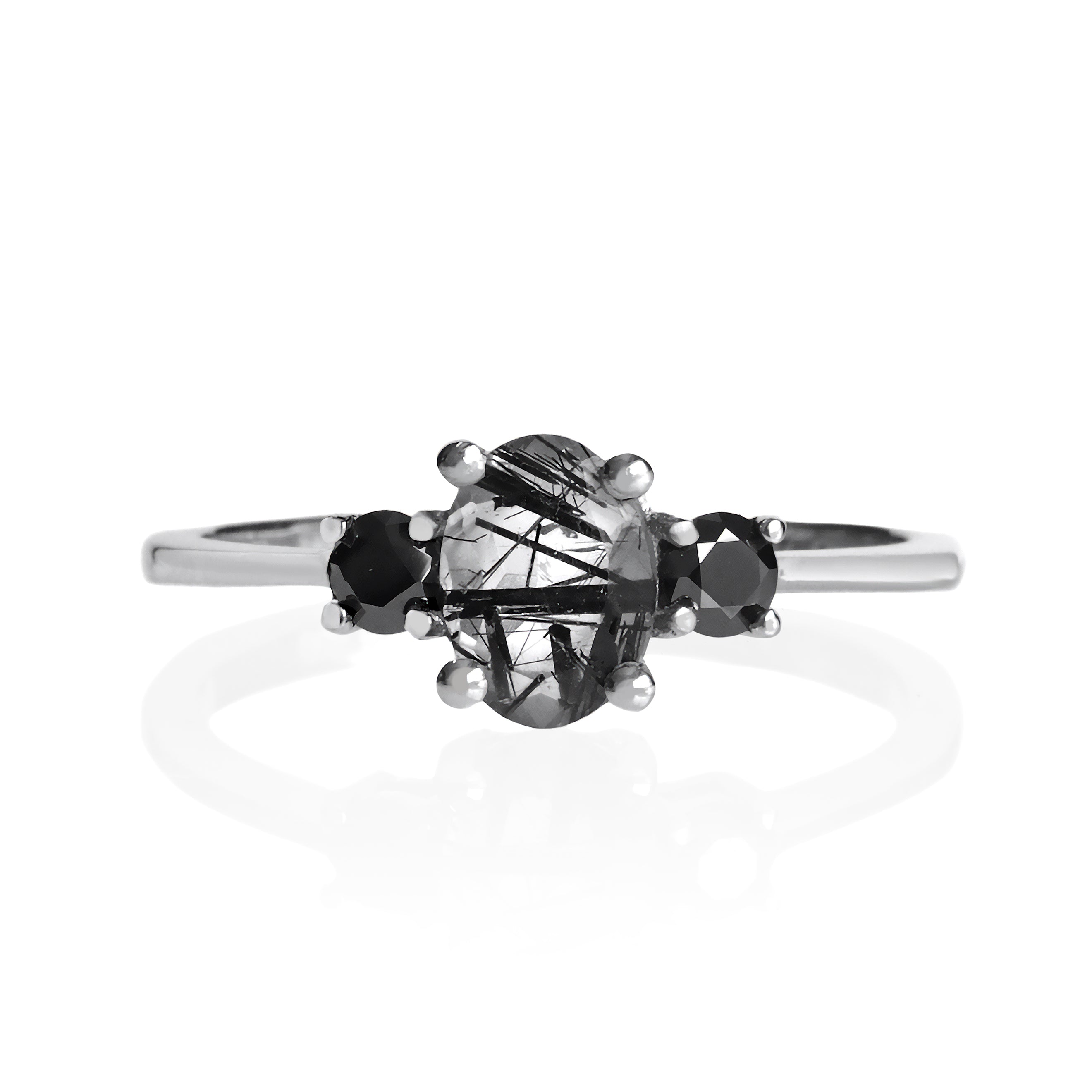 A product photo of a faceted Tourmalated Quartz and black moissanite ring in solid sterling silver on a white background. The faceted cut of the tourmalated stone allows the viewer to see every angle of the needle-like inclusions within, while the black diamonds echo the dark colouring of the centre stone.