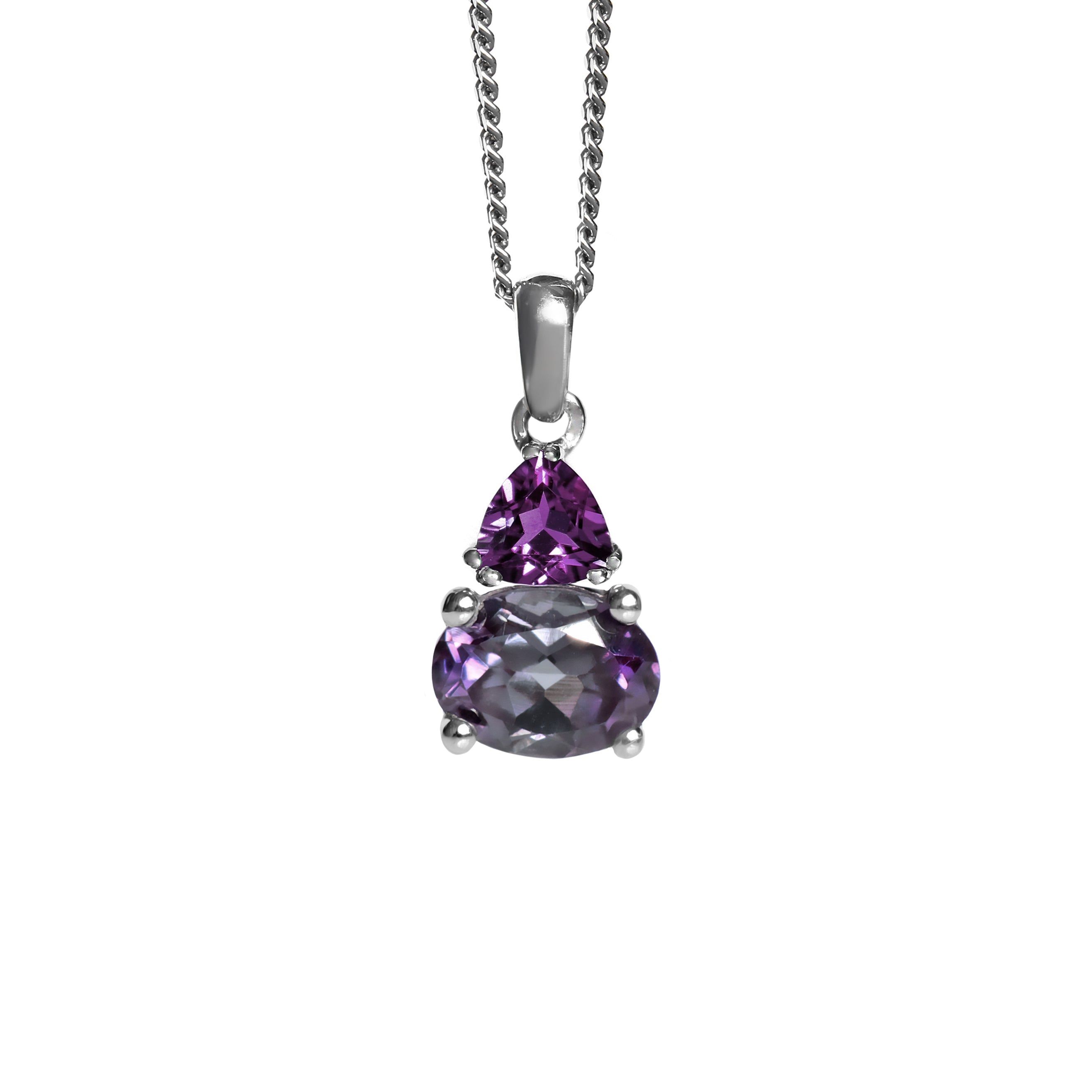 A product photo of a silver lab alexandrite and natural deep purple amethyst necklace suspended against a white background. The horizontally-oriented alexandrite stone is held in place by 4 pairs of claws at its top and bottom, with a 5mm deep purple amethyst birthstone gem connecting the stone to the rest of the pendant. It is suspended by a simple silver chain.