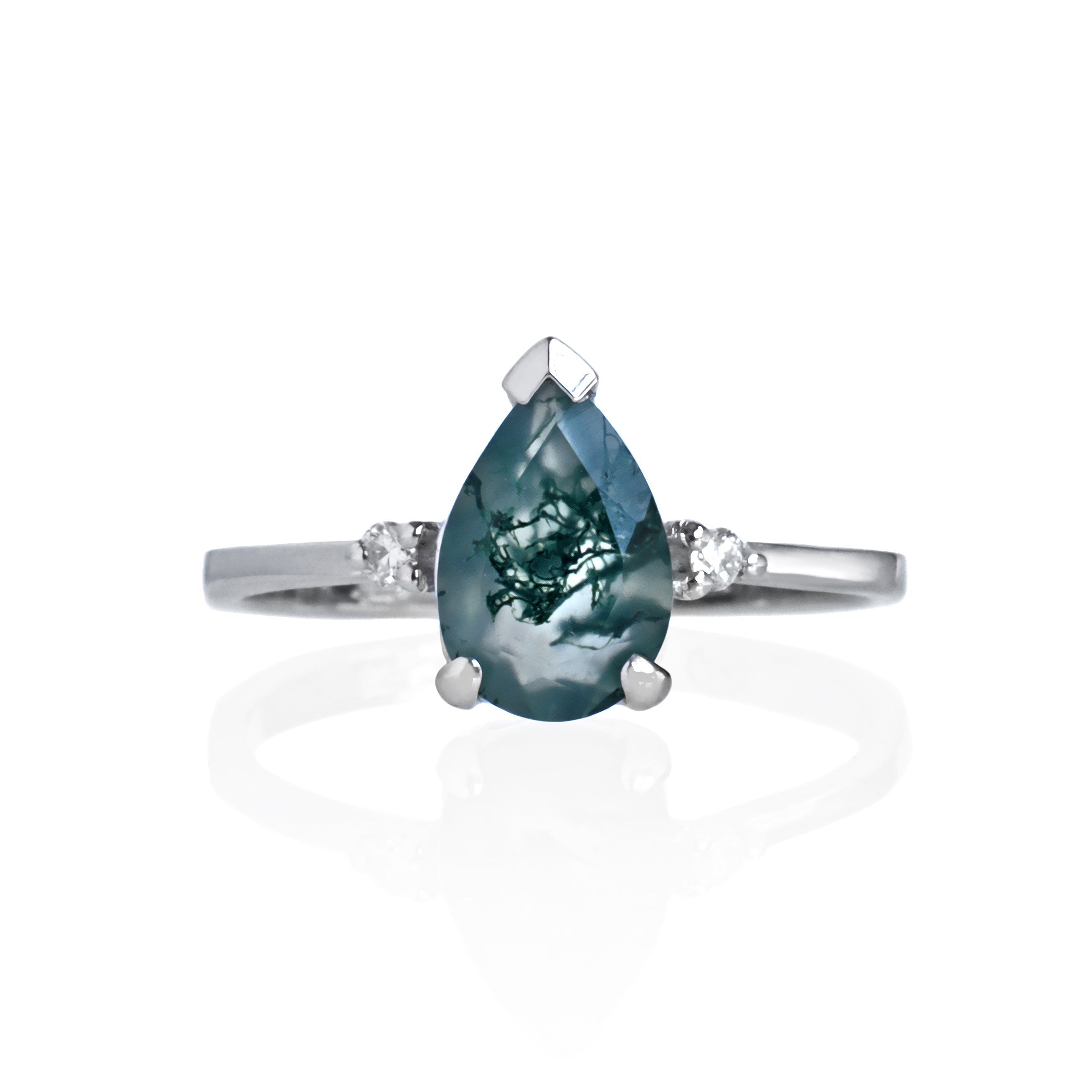 A product photo of a solid sterling silver ring with a pear-cut moss agate centre stone sitting on a white background. The silver band is simple and smooth, meeting elegantly on either side of the centre stone, hugged by a single white moissanite jewel on either side.