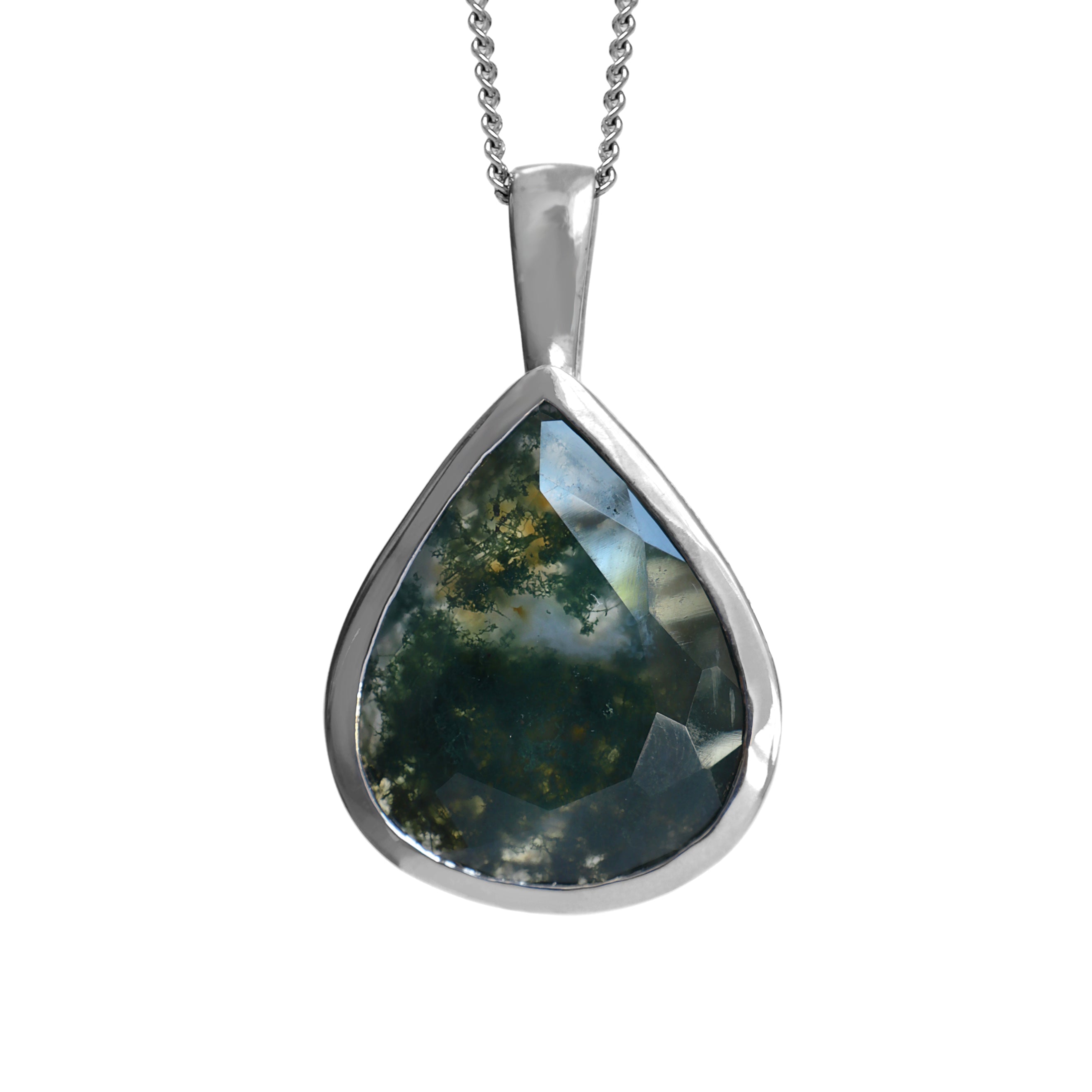 A product photo of a silver moss agate statement pendant suspended by a silver chain over a white background. The pendant features a teardrop-shaped moss agate stone set in a sleek silver bezel. 1 The stone is primarily a deep, forest green with cloudy white and grey inclusions that create a landscape-like effect. Facets are visible on the lower portion of the stone, adding a subtle sparkle.