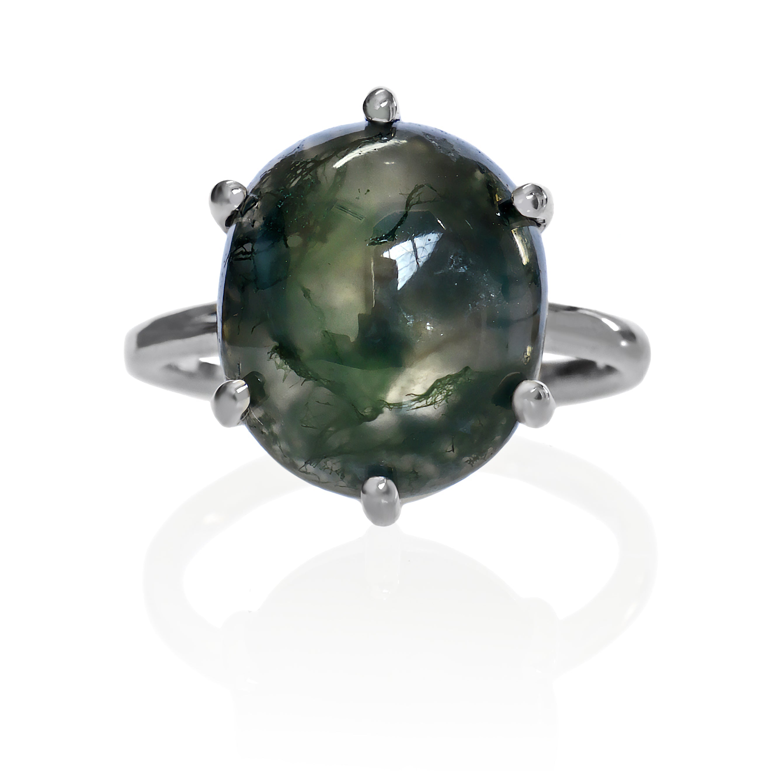 A product photo of a moss agate statement ring in solid sterling silver, featuring a hand-cut moss agate centre stone on a white background. The ring features a large, oval 14.2 x 12.4mm hand-cut stone with a translucent, milky base. Unique green moss-like inclusions create organic patterns within. Held by six small, round silver prongs, the ring has a smooth silver band.