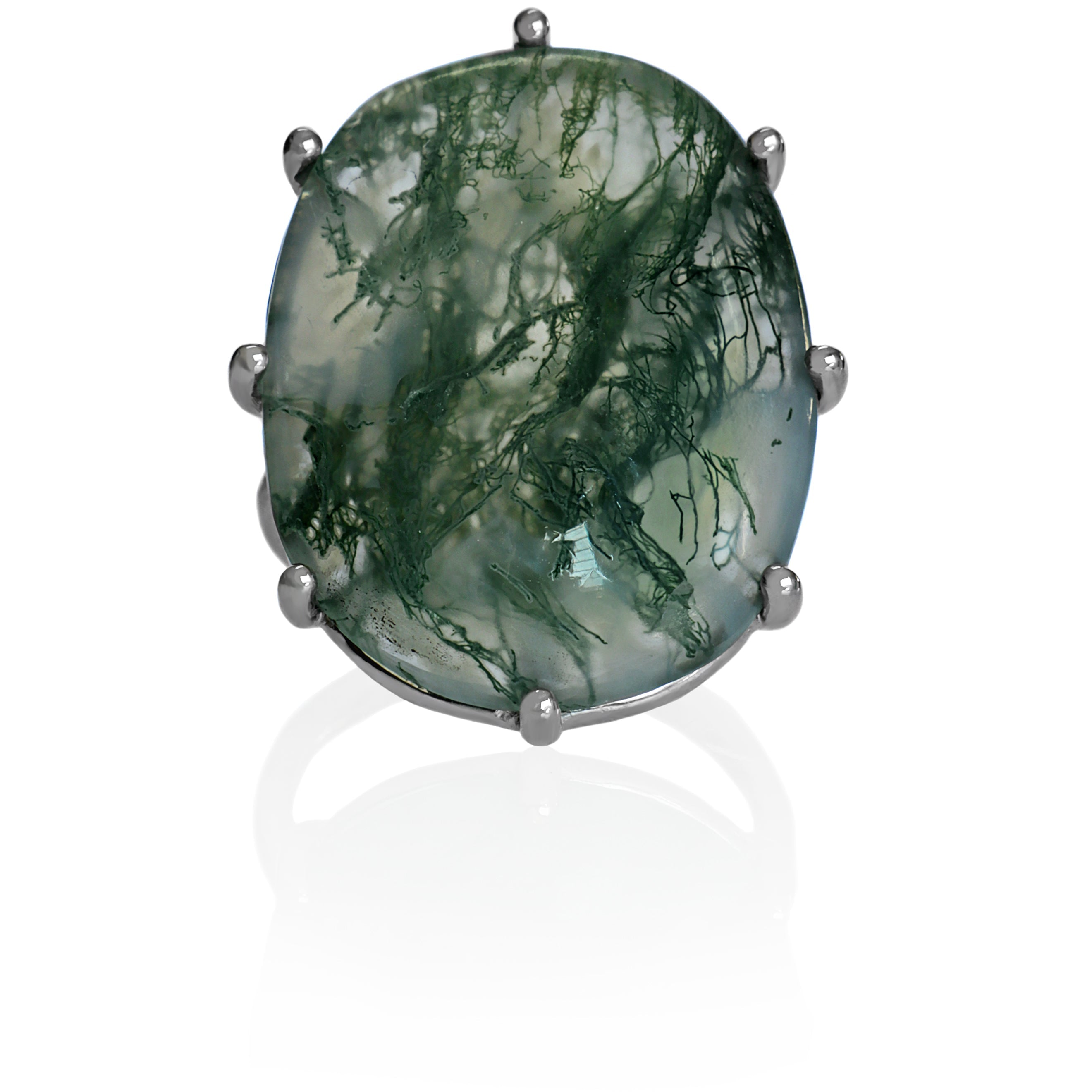 A product photo of a moss agate statement ring in solid sterling silver, featuring a hand-cut moss agate centre stone on a white background. The ring features a very shallow, oval 25.5 x 19.8mm cabochon with a pale base tone. Delicate, fine lines of dark green inclusions create a wispy, ethereal pattern throughout the stone. Held by eight small, round silver prongs, the ring has a smooth silver band.