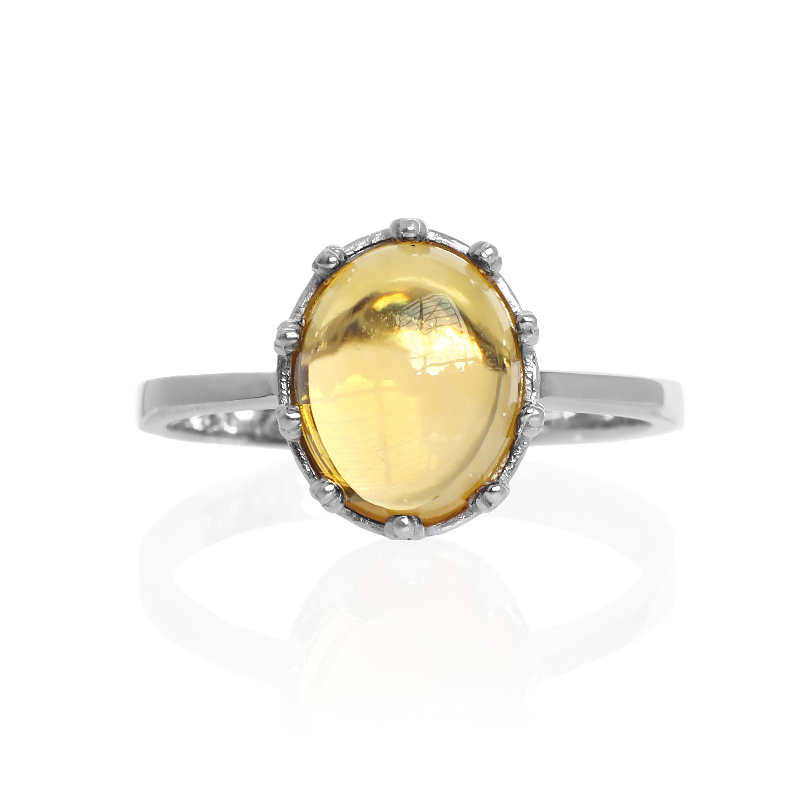 A product photo of a 925 sterling silver citrine birthstone ring sitting on a white background. The fiery orange yellow citrine stone is impressively large, with the cabochon cut allowing the viewer to look into the stone like a crystal ball. The 10x8mm oval stone is encased in ornate silver detailing, almost like a royal crown.