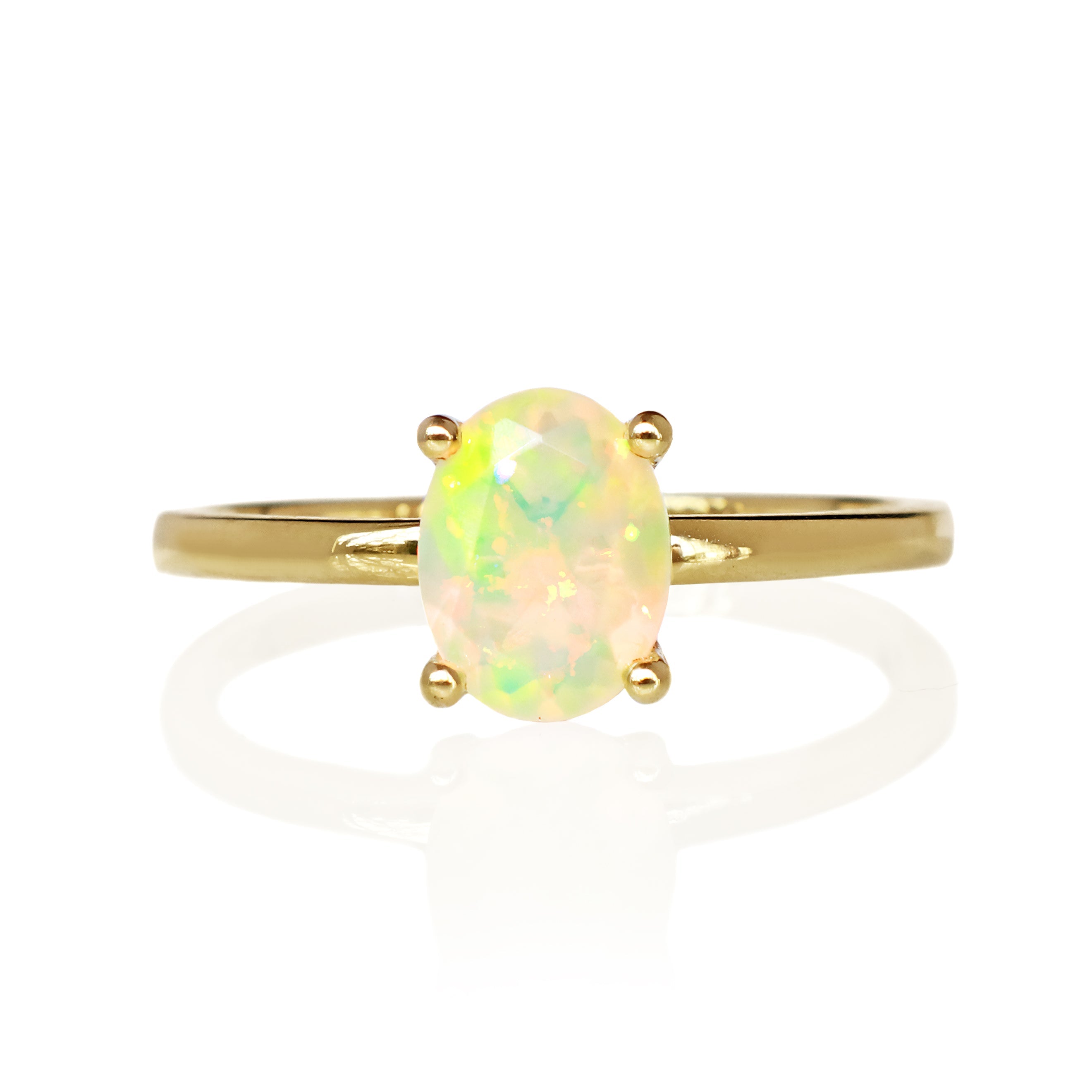 A product photo of an oval yellow gold solitaire ring on a white background. The band is rounded and smooth, and the 8x6mm faceted hydrophane Ethiopian opal gemstone, glinting in the light, is held in place by 4 delicate golden claws.