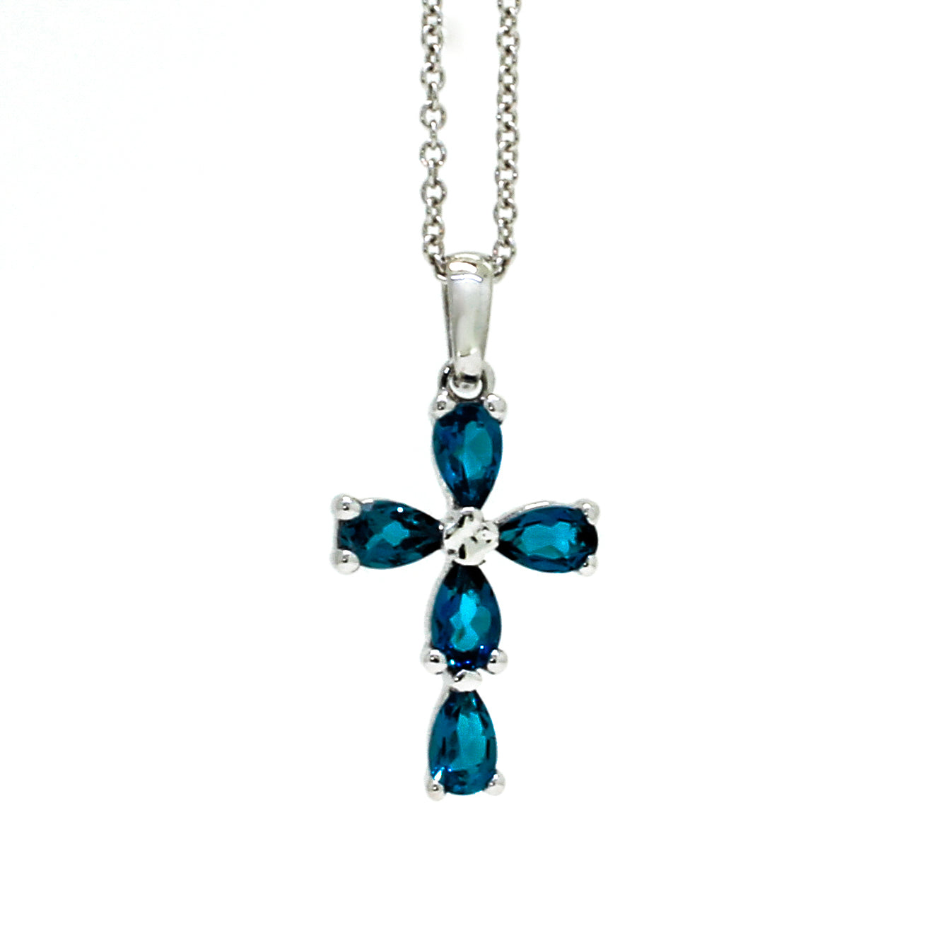A product photo of a white gold london blue topaz pendant sitting against a white background. The ornate pendant is cross-shaped, made up of 5 pear-cut topaz stones and simplistic white gold detailing. It is suspended by a simple white gold chain.