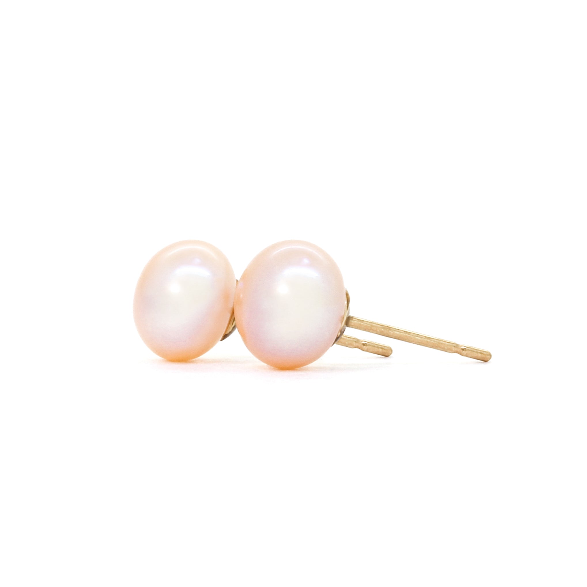 A product photo of simple peach-coloured pearl yellow gold earring studs on a white background.
