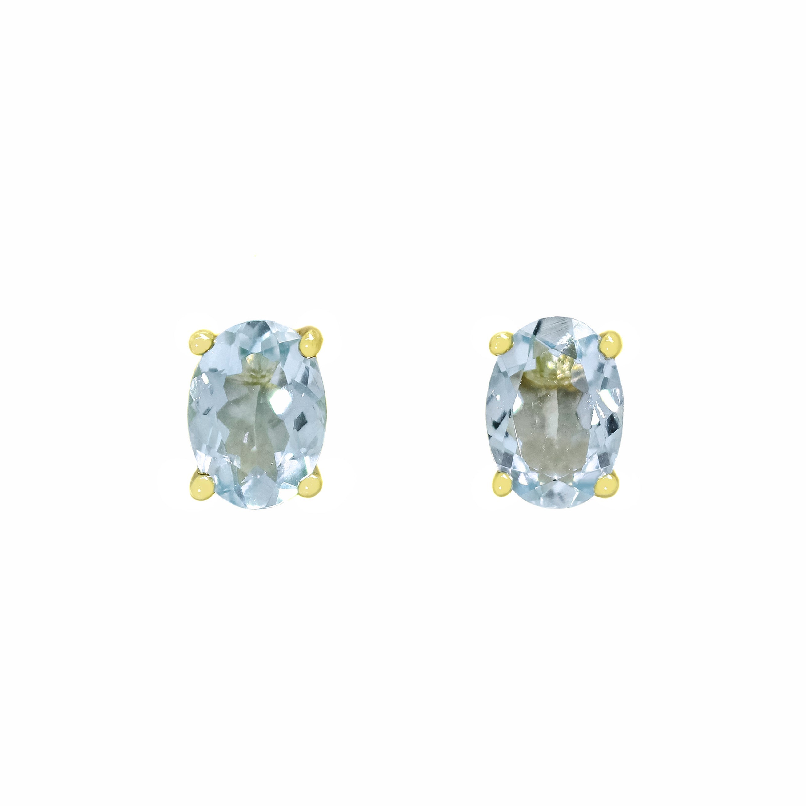 A product photo of 7x5mm Oval Shaped Aquamarine Earring Studs in 9k Yellow Gold sitting on a plain white background. The 2 aquamarine stones measure 5mm across and are a light blue colour, reflecting baby blue hues across their multi-faceted edges, and are each held in place by dainty golden claws.