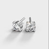 A turntable video of a pair of 9 karat white gold lab diamond stud earrings sitting in the sun on a white textured background. The brilliant, colourless half pointer round diamonds measure approximately 4mm across, and are held in place by a simple 4-claw setting.