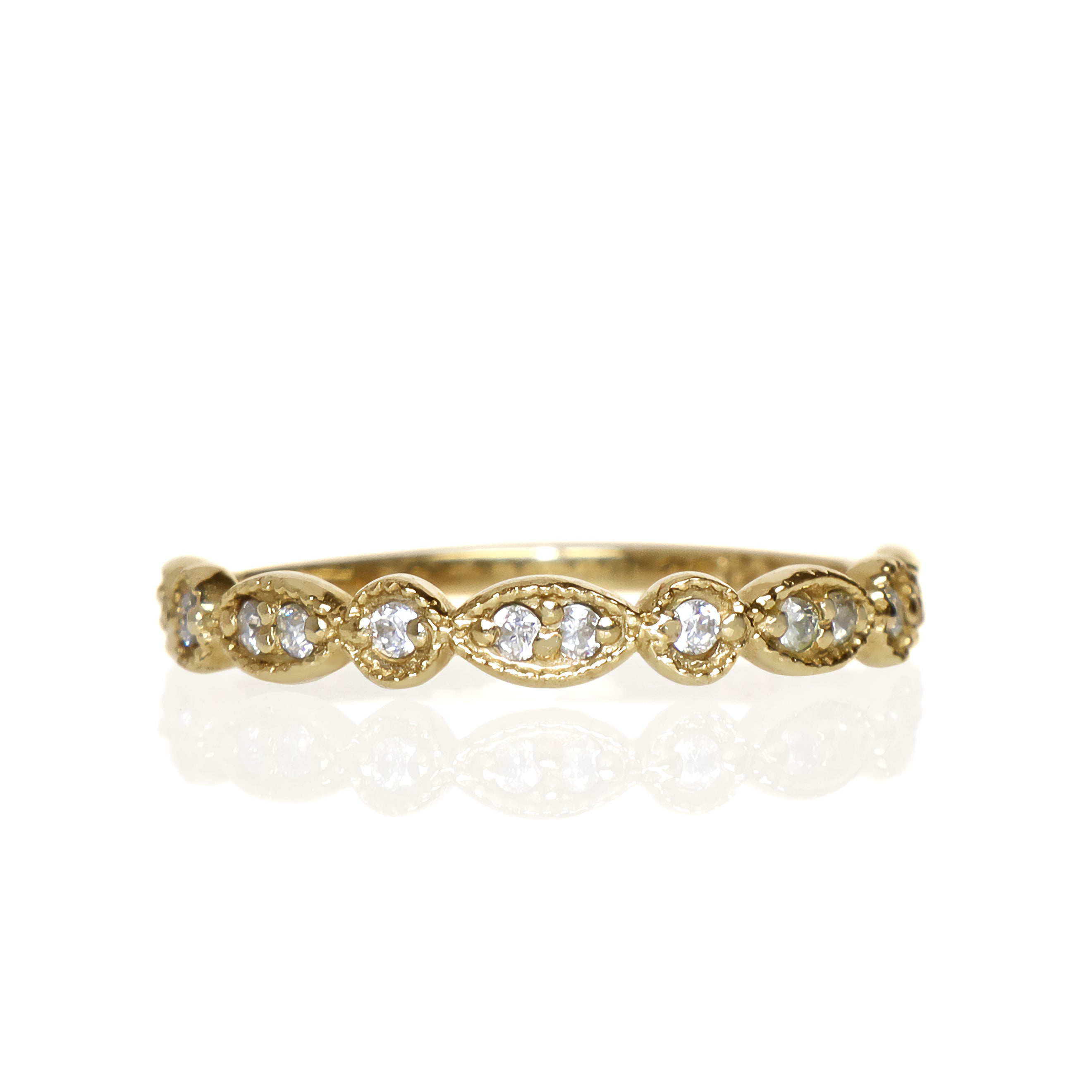 A product photo of an ornate moissanite ring in 9k yellow gold. Oval gold frames adorned with two small moissanite gems each alternate with circular gold frames adorned with singular moissanite gems, making up the ring for about half of its length before smoothing out into a simple flat yellow gold band. 