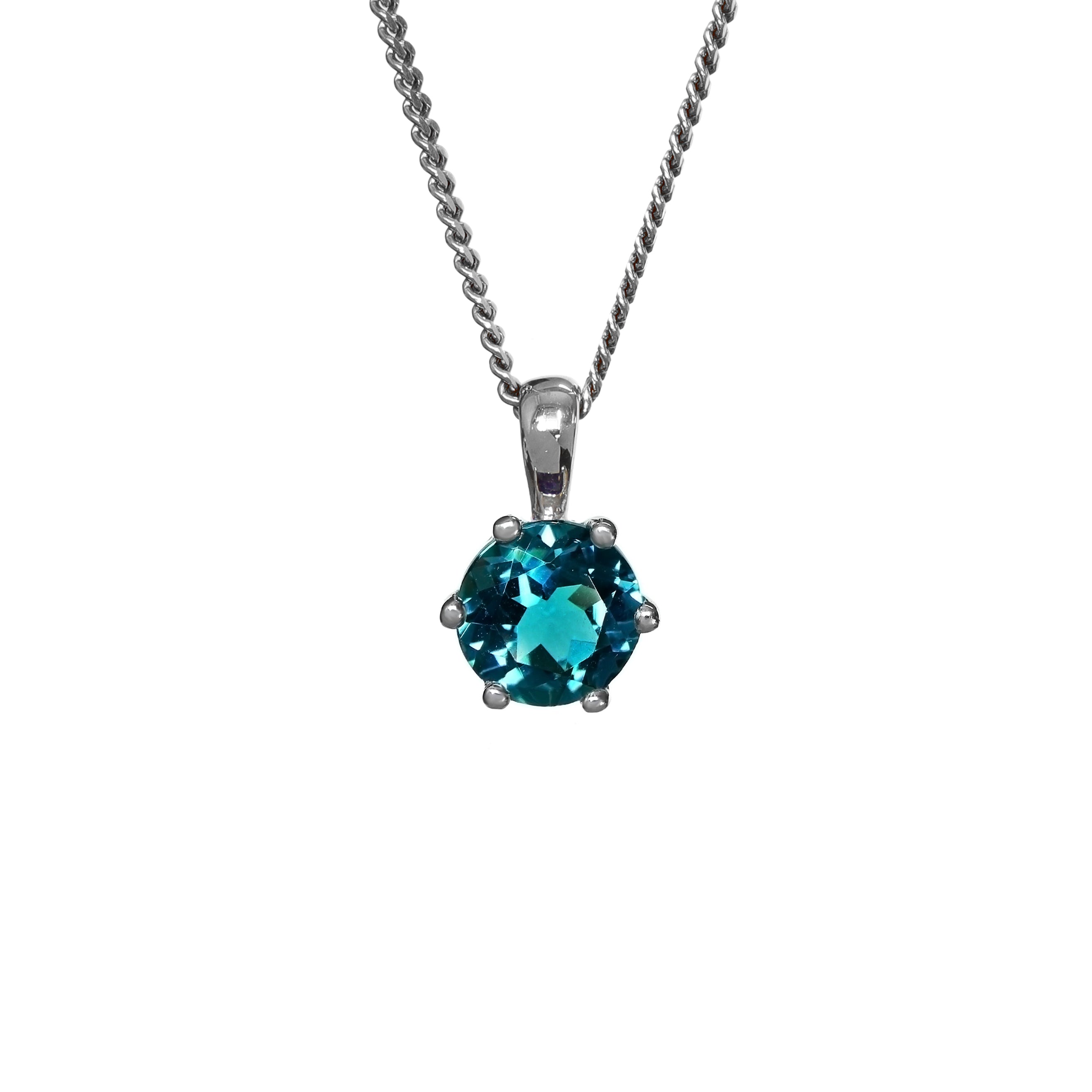A product photo of a white gold london blue topaz pendant sitting against a white background. The highly-reflective circle cut topaz stone is held in place by 6 dainty white gold claws. It is suspended by a simple white gold chain.