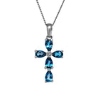 A product photo of a white gold london blue topaz pendant sitting against a white background. The ornate pendant is cross-shaped, made up of 5 pear-cut topaz stones and simplistic white gold detailing. It is suspended by a simple white gold chain.