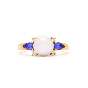 A product photo of a rose gold ring with a rosaline pearl in the centre, hugged by a tanzanite and two diamond jewels on either side.