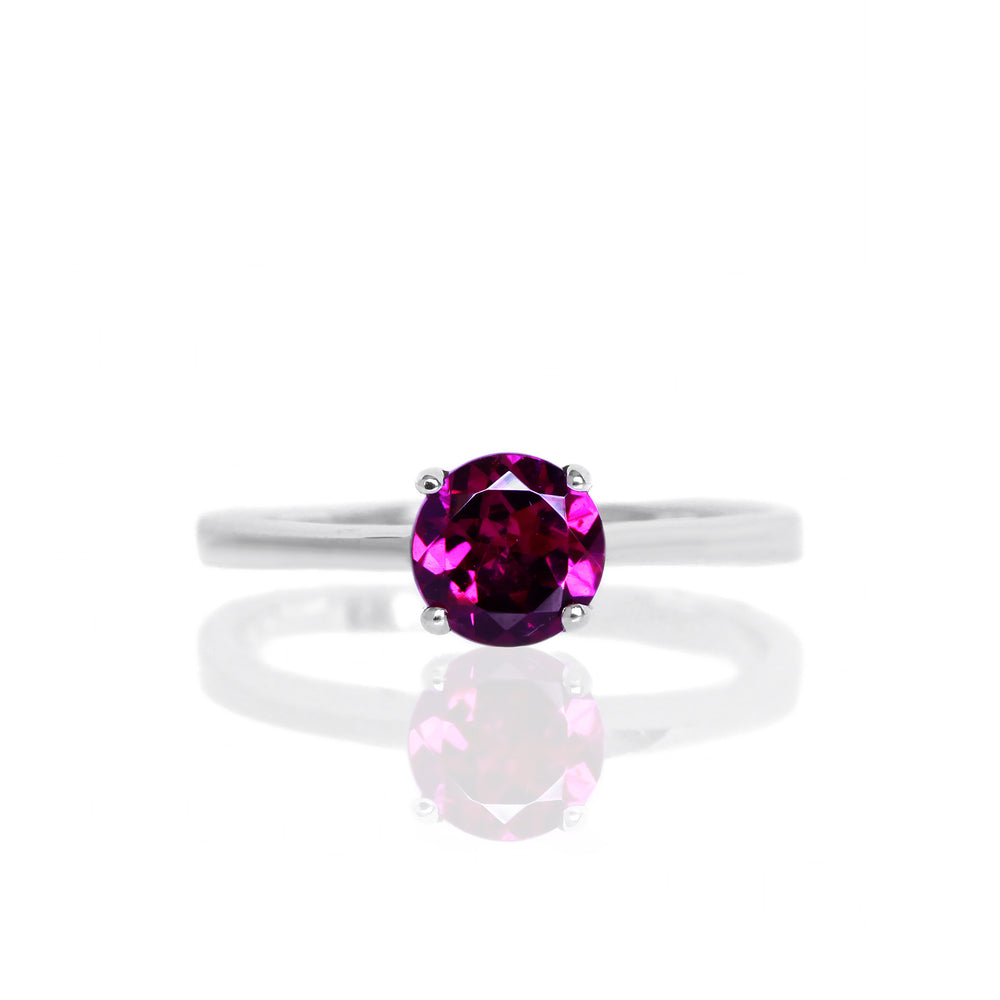 
            
                Load image into Gallery viewer, A product photo of a silver ring with a round-cut rhodalite centre stone sitting on a white background. The silver band is simple and smooth, connecting on either side of a round-cut rhodalite stone held in place by four delicate silver claws. The rhodalite jewel is a deep velvet purple colour, reflecting a warm plum colours across its multi-faceted surface.
            
        
