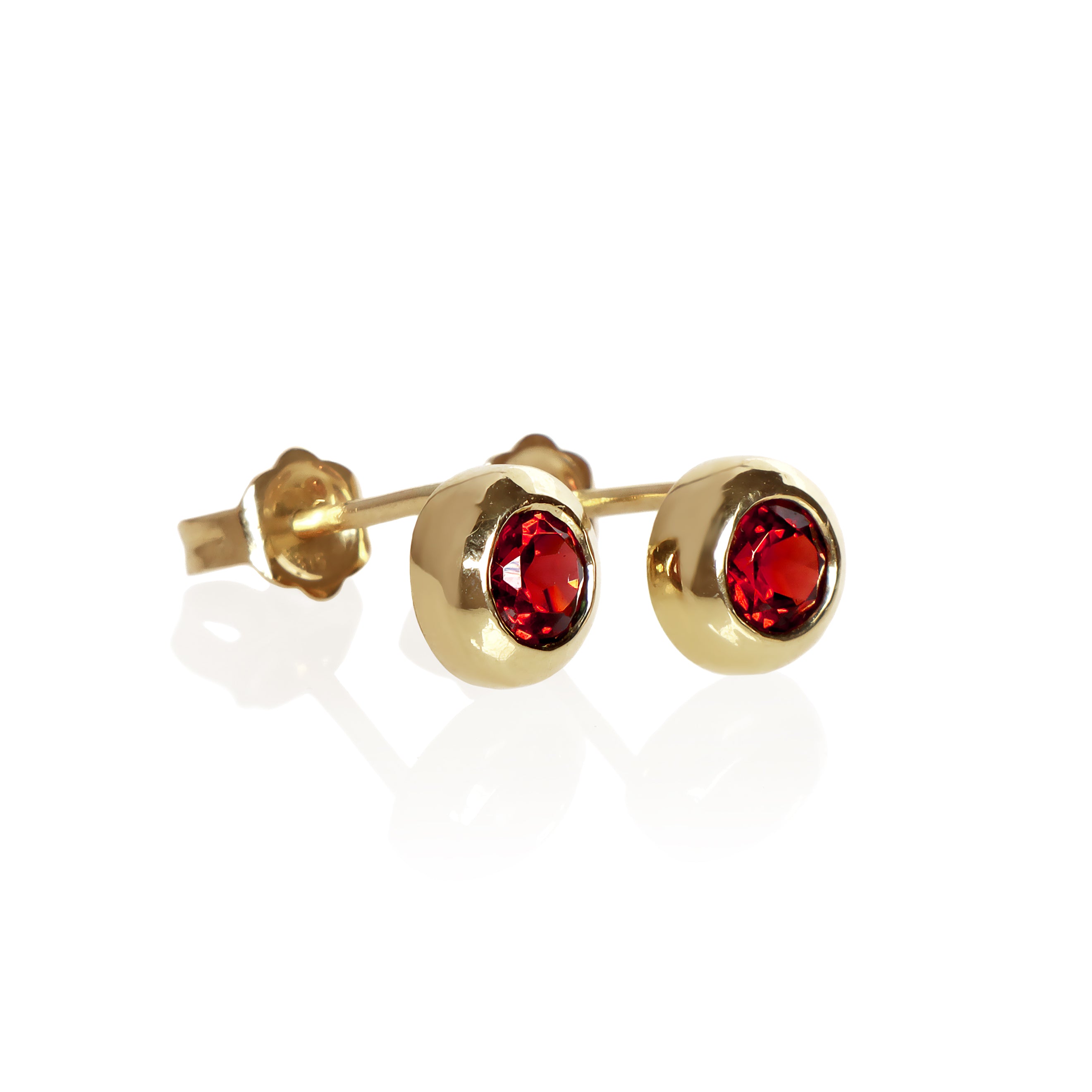 A product photo of 4mm Round Bezel-Set Garnet Earring Studs in 9k Yellow Gold sitting on a plain white background. The 2 garnet stones measure 4mm across and are deep red, reflecting sanguine hues across their multi-faceted edges, framed in a thick layer of yellow gold.