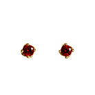 A product photo of 3.5mm Round Garnet Earring Studs in 9k Yellow Gold sitting on a plain white background. The stones are held in place by 4 delicate golden claws arranged in a flower-like pattern where they meet the stud. The garnets reflect sanguine hues across their multi-faceted edges.