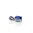 A product photo of a white gold tanzanite pendant suspended by a chain against a white background. The oval stone is held in place by 4 small claws, and reflects violet blue and indigo colours from its many edges.