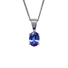 A product photo of a white gold tanzanite pendant suspended by a chain against a white background. The oval stone is held in place by 4 small claws, and reflects violet blue and indigo colours from its many edges.