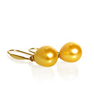A product photo of a simple pair of yellow gold shepherd's hook earrings suspending two golden pearls over a white background.