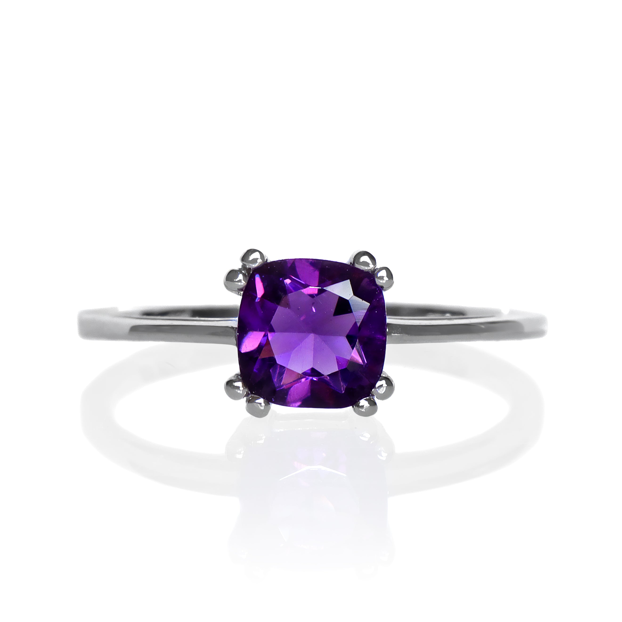 A product photo of a white gold ring with a large cushion-cut amethyst centre stone on a white background. The band is smooth gold, and the deep purple amethyst centre stone is held in place by 8 little claws, 2 on each corner.