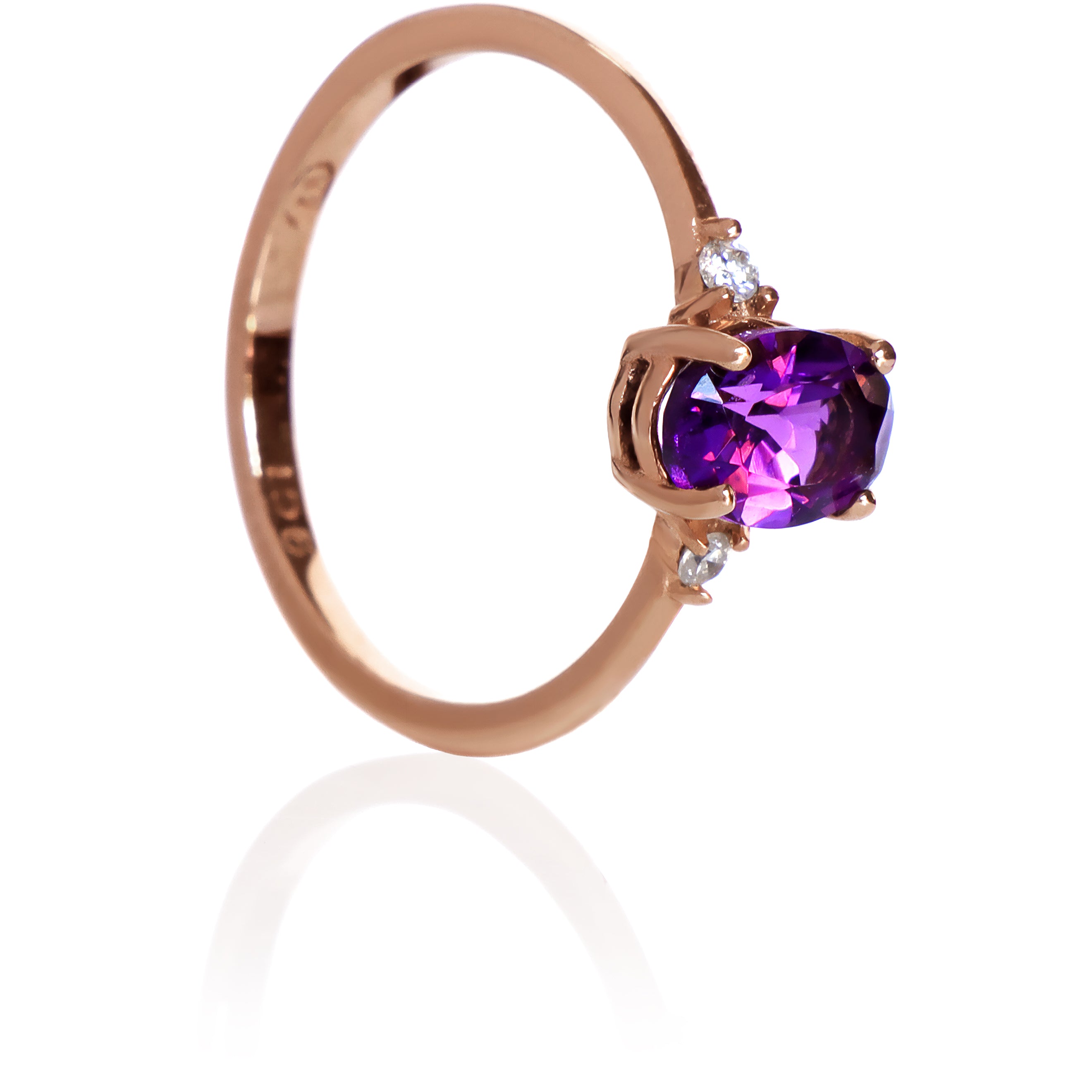 A product photo of a rose gold amethyst ring sitting against a white background. The rose gold band is plain and smooth, and the centre oval-cut deep purple amethyst stone is framed by a single white diamond on either side.