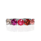 A product photo of a bold, multi-gemstone ring in 9k white gold – made up of 5 pink & red coloured jewels – sitting on a white background. From left to right, 4.5mm round-cut pink tourmaline, garnet, ruby with stunning streaked inclusions, grape garnet and morganite stones make up a boldly feminine statement piece.