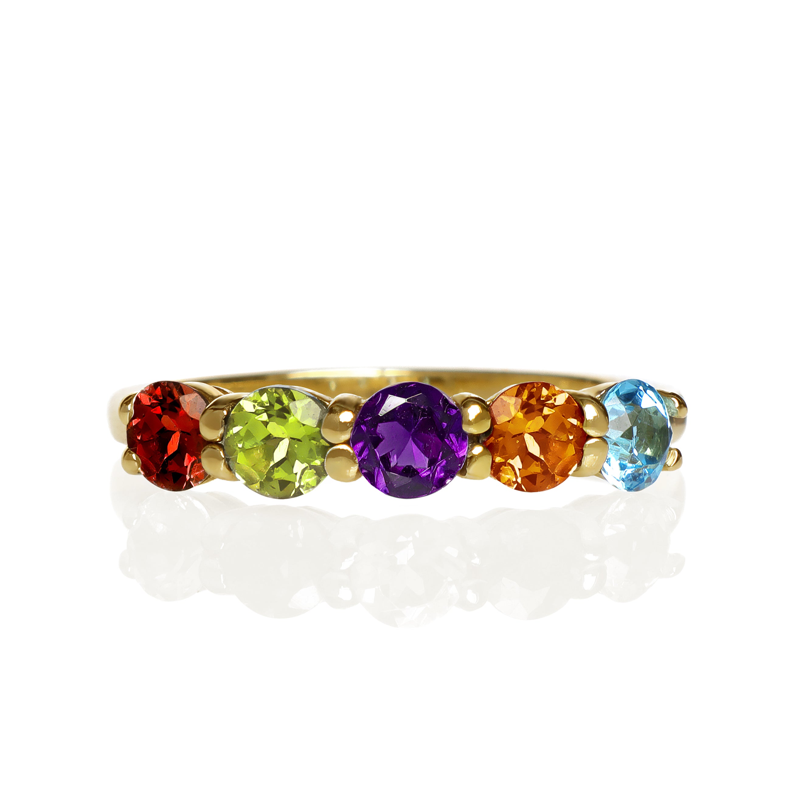 A product photo of a bold, multi-gemstone ring in 9k yellow gold – made up of rainbow-coloured jewels – sitting on a white background.