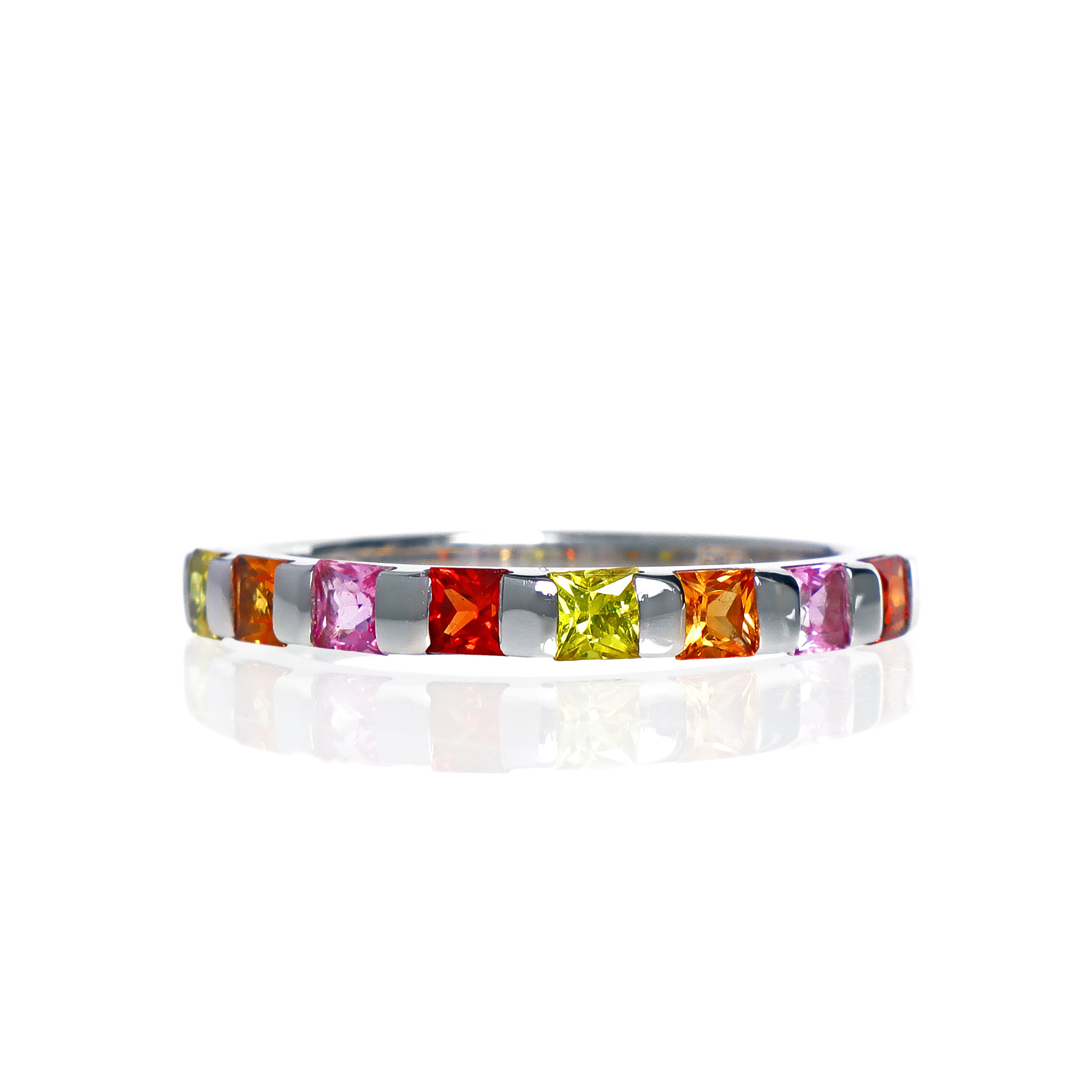 A product photo of a bold, multi-gemstone stacking ring in 9k white gold – made up of multi-coloured sapphire jewels – sitting on a white background.