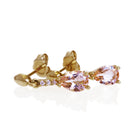 A product photo of 7x5mm Pear Morganite & Diamond Earrings in 9k Yellow Gold sitting on a plain white background. A golden strip connects the morganites to the studs, each strip adorned with 3 diamonds each. The morganites reflect light pinky hues across their multi-faceted edges.