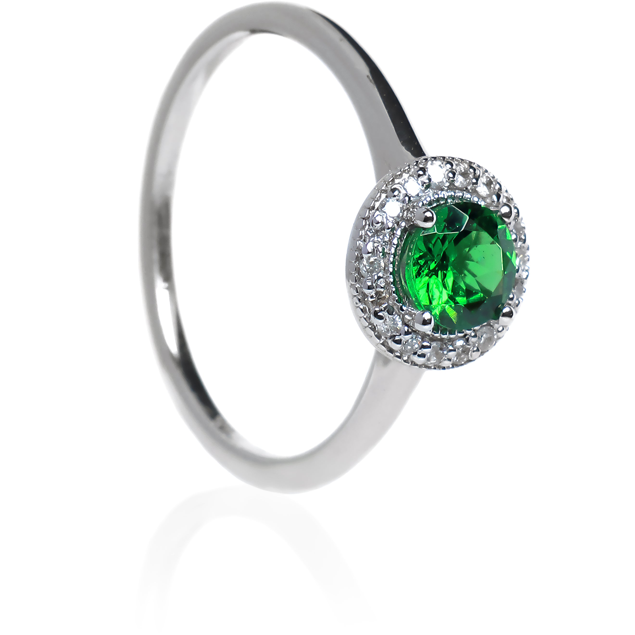 A product photo of a classic diamond halo tsavorite ring in solid 9k white gold on a white background. The diamond halo is framed by a thick band of solid 9k white gold, and the rounded band is smooth and minimalistic. The deep, verdant-green tsavorite centre stone is held in place by 4 claws and reflects light off of its many facets. The green gemstone colour would be a good emerald substitute.