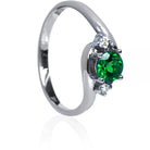 A product photo of a mystical tsavorite and diamond fantasy ring in solid 9k white gold on a white background. The deep, verdant-green tsavorite is held in place by 4 claws and reflects light off of its many facets, while the diamonds on either side are held by 3 each. The smooth white gold band curves elegantly, meeting at the top and bottom of the tsavorite and diamond arrangement. The green gemstone colour be a good emerald substitute.