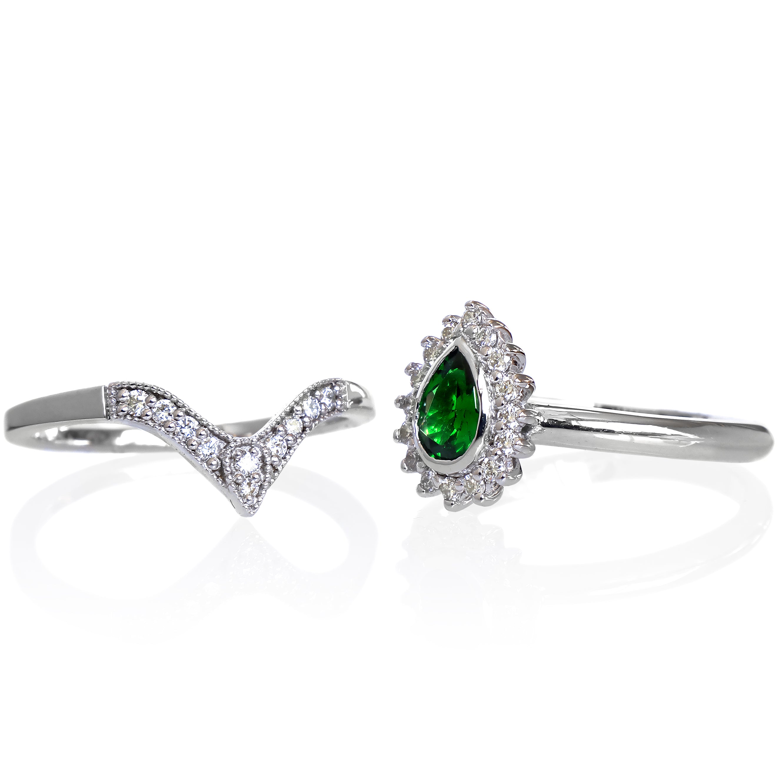 A product photo of a bridal/wedding set made of solid 9k white gold. The engagement ring is made up of a pear-shaped tsavorite gemstone, framed by a halo of diamonds and elegant gold detailing. The band is rounded and smooth, making for comfortable wear. The wedding band is designed to match the engagement ring perfectly, with 10 diamonds embedded along its length to echo the halo that frames the engagement ring's stone. The green gemstone colour would be a good emerald alternative for wearers born in May.