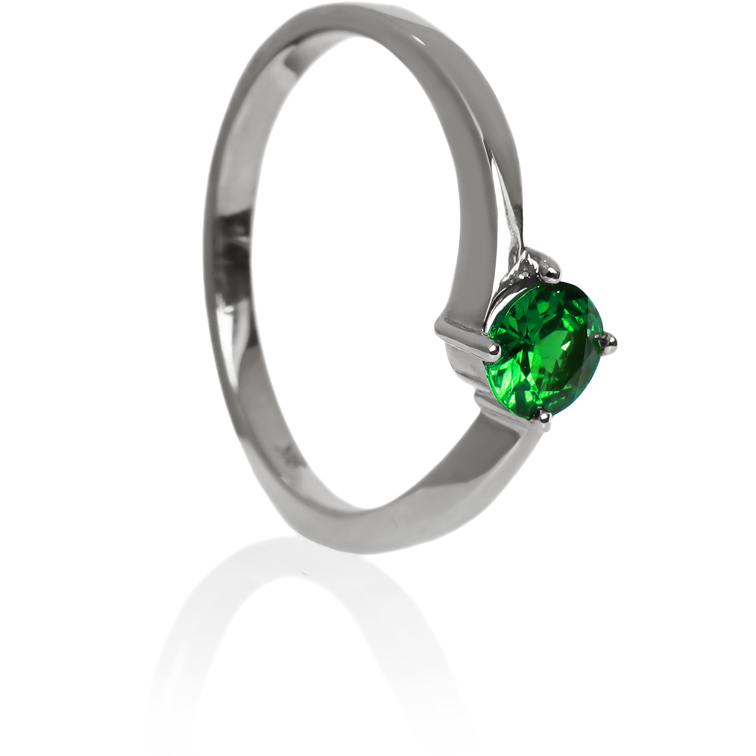 A product photo of a curved-band 9k white gold solitaire ring with a verdant-green tsavorite centre stone sitting on a white background. The green gemstone colour would be a good emerald substitute.
