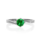 A product photo of a curved-band 9k white gold solitaire ring with a verdant-green tsavorite centre stone sitting on a white background. The green gemstone colour be a good emerald substitute.