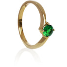 A product photo of a curved-band 9k yellow gold solitaire ring with a verdant-green tsavorite centre stone sitting on a white background. The green gemstone colour would be a good emerald substitute.