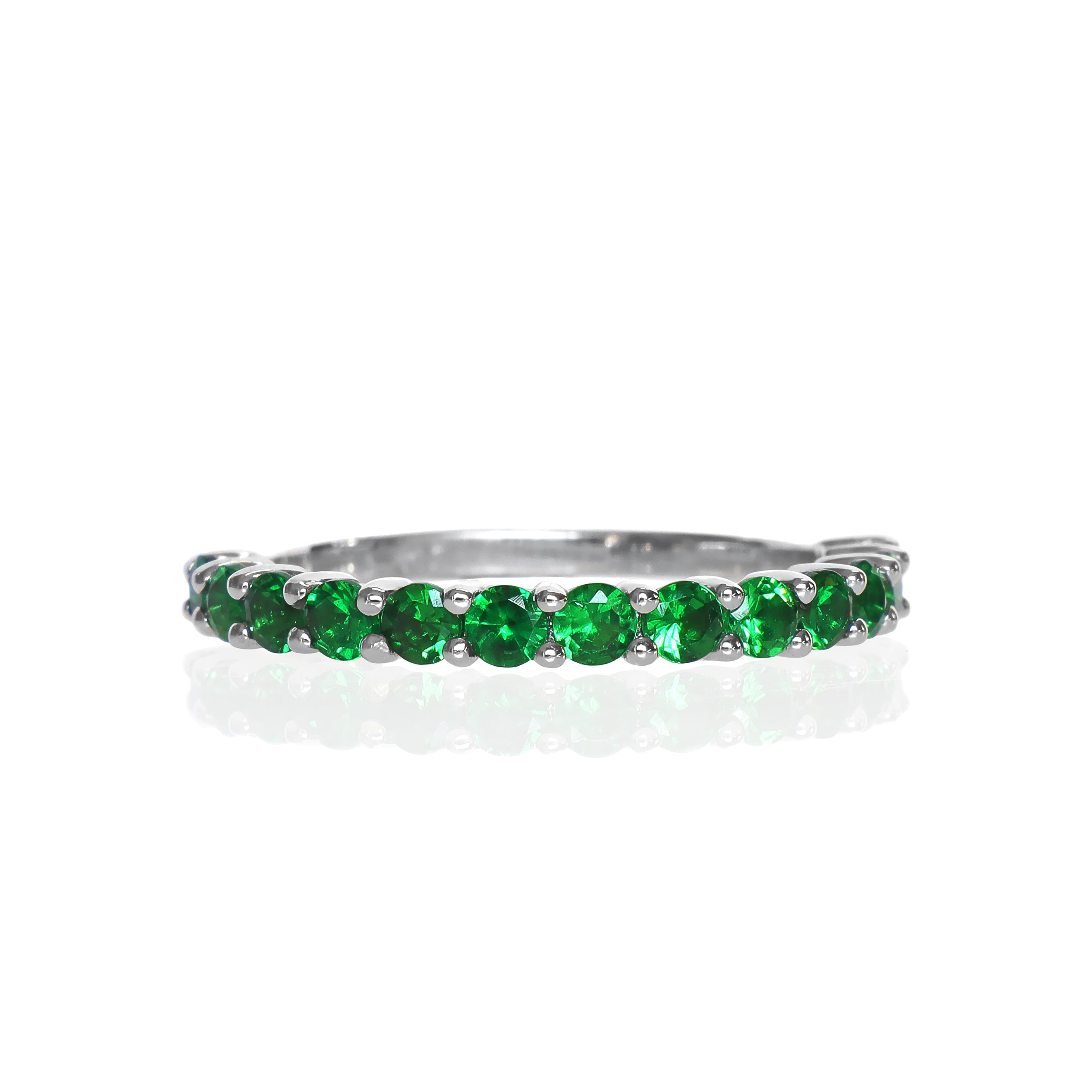 A product photo of a white gold eternity band with 13 tsavorite stones embedded along its length on a white background. The green gemstone colour would be a good emerald substitute.