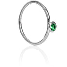 A product photo of a delicate white gold stacking ring with a tiny, bezel-set mint green tourmaline in the centre sitting on a white background. The band is slim and thread-like, with the focus drawn to the petite 3mm glinting green centre stone. The green gemstone colour would be a good emerald substitute.