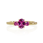 A product photo of a dainty and elegant yellow gold ring with a stunning trio of grape garnets sitting against a white background. The largest of the stones sits in the centre, an oval 6x4mm grape garnet - hugged by two smaller circular warm purple stones on either side.