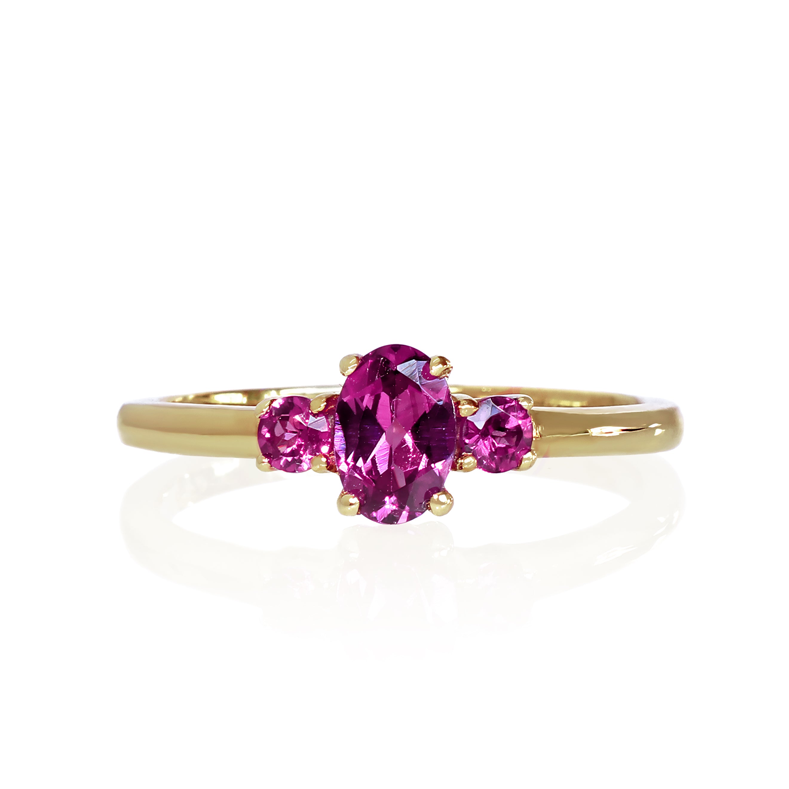 A product photo of a dainty and elegant yellow gold ring with a stunning trio of grape garnets sitting against a white background. The largest of the stones sits in the centre, an oval 6x4mm grape garnet - hugged by two smaller circular warm purple stones on either side.