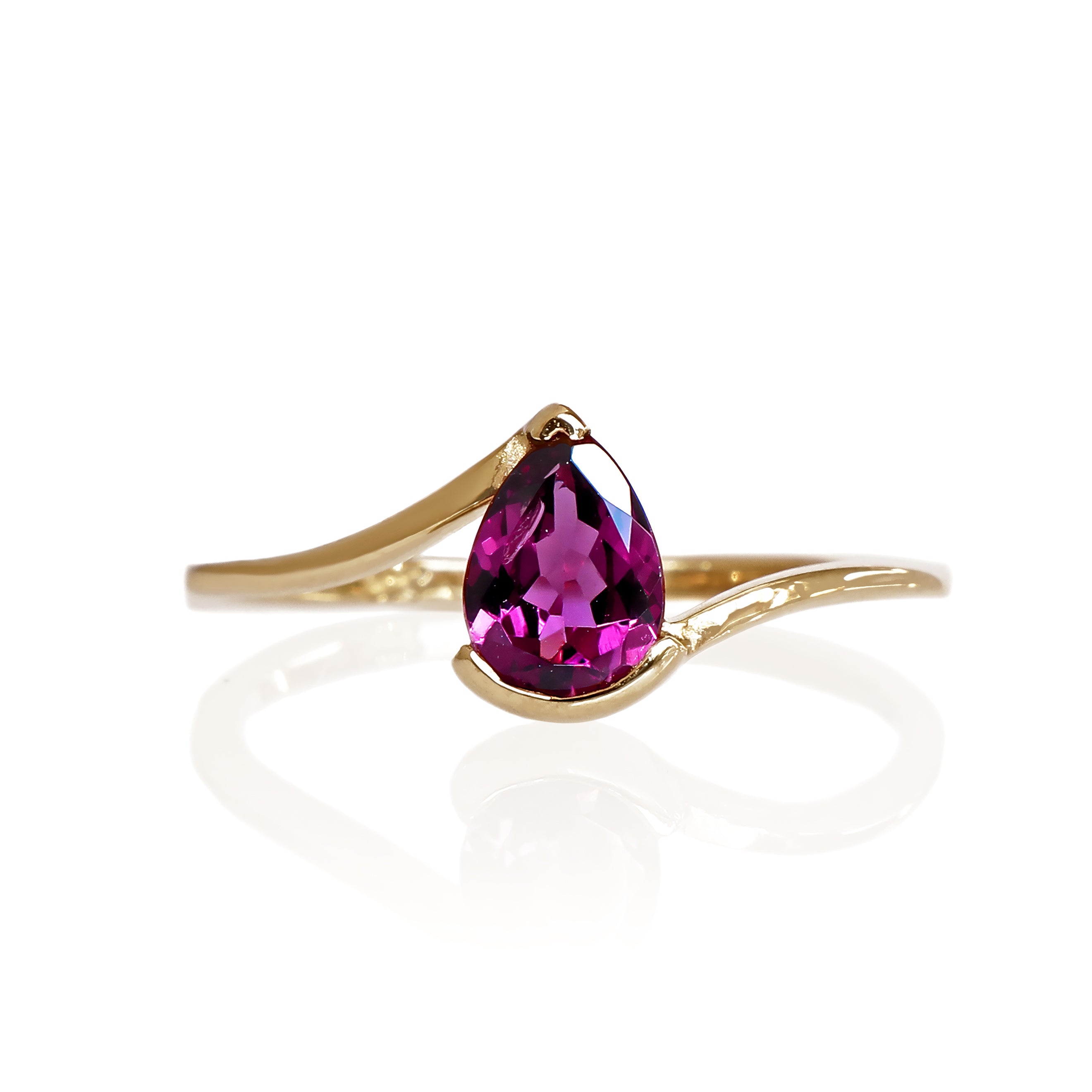 A product photo of a yellow gold grape garnet ring sitting against a white background. The gold band is plain and smooth, and curves to meet at the top and bottom of a large, 7x5mm pear shaped grape garnet centre stone - holding it in place.