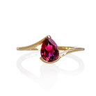 A product photo of a yellow gold rhodalite ring sitting against a white background. The gold band is plain and smooth, and curves to meet at the top and bottom of a large, 7x5mm pear shaped rhodalite centre stone - holding it in place.