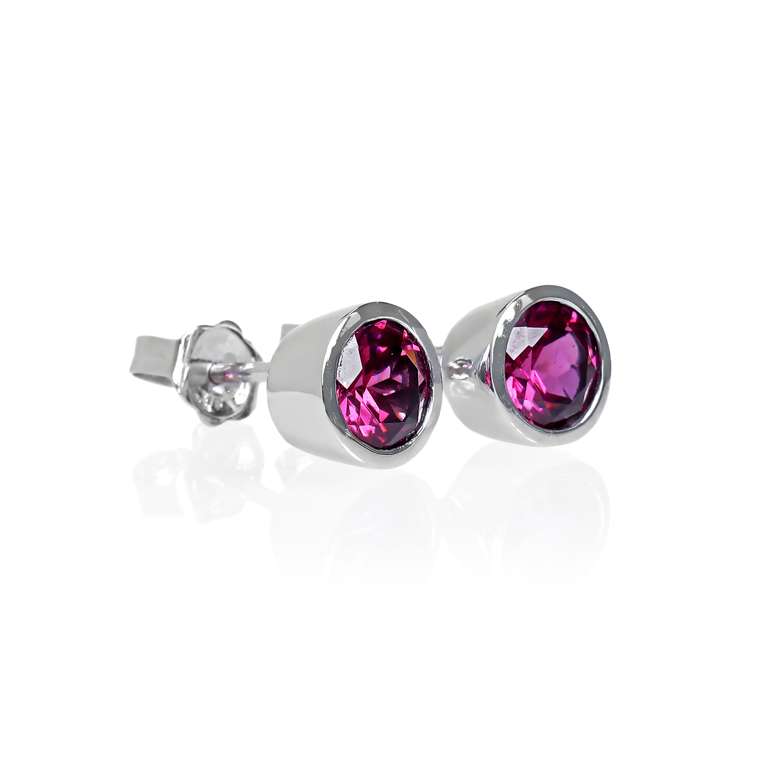 A product photo of white gold grape garnet earrings sitting on a white background. The round stones are encased in a thick layer of white gold bezel framing. The grape garnet purple-coloured gemstones reflect warm pink and purple light from their many edges.